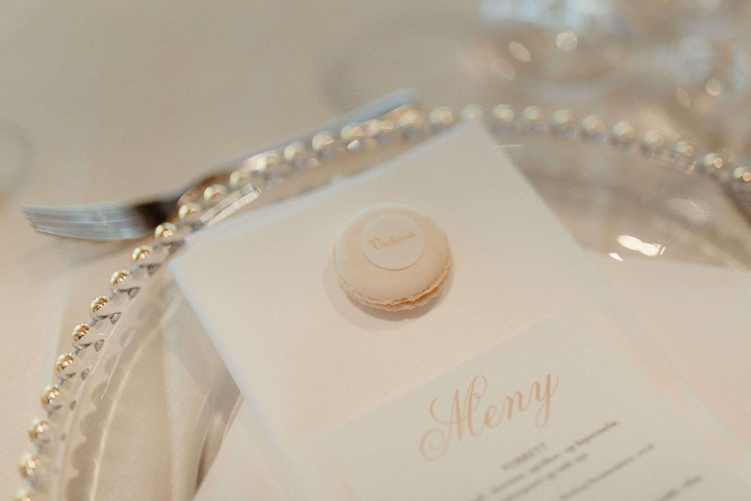 Close-up detail of elegant wedding table settings with crystal glassware and beaded charger plates in soft beige tones.