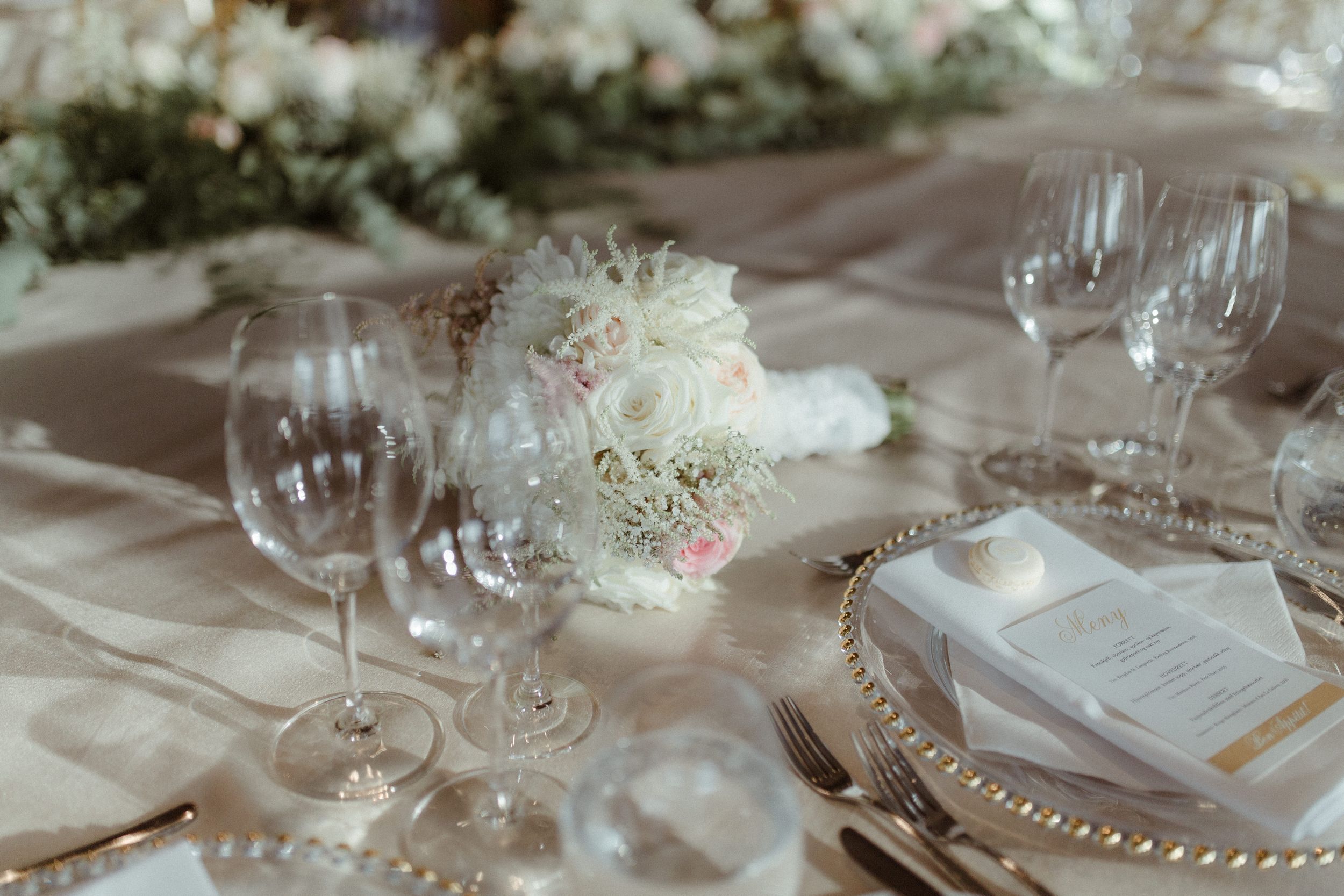 Elegant white floral table arrangements with crystal glassware at a luxury wedding reception.