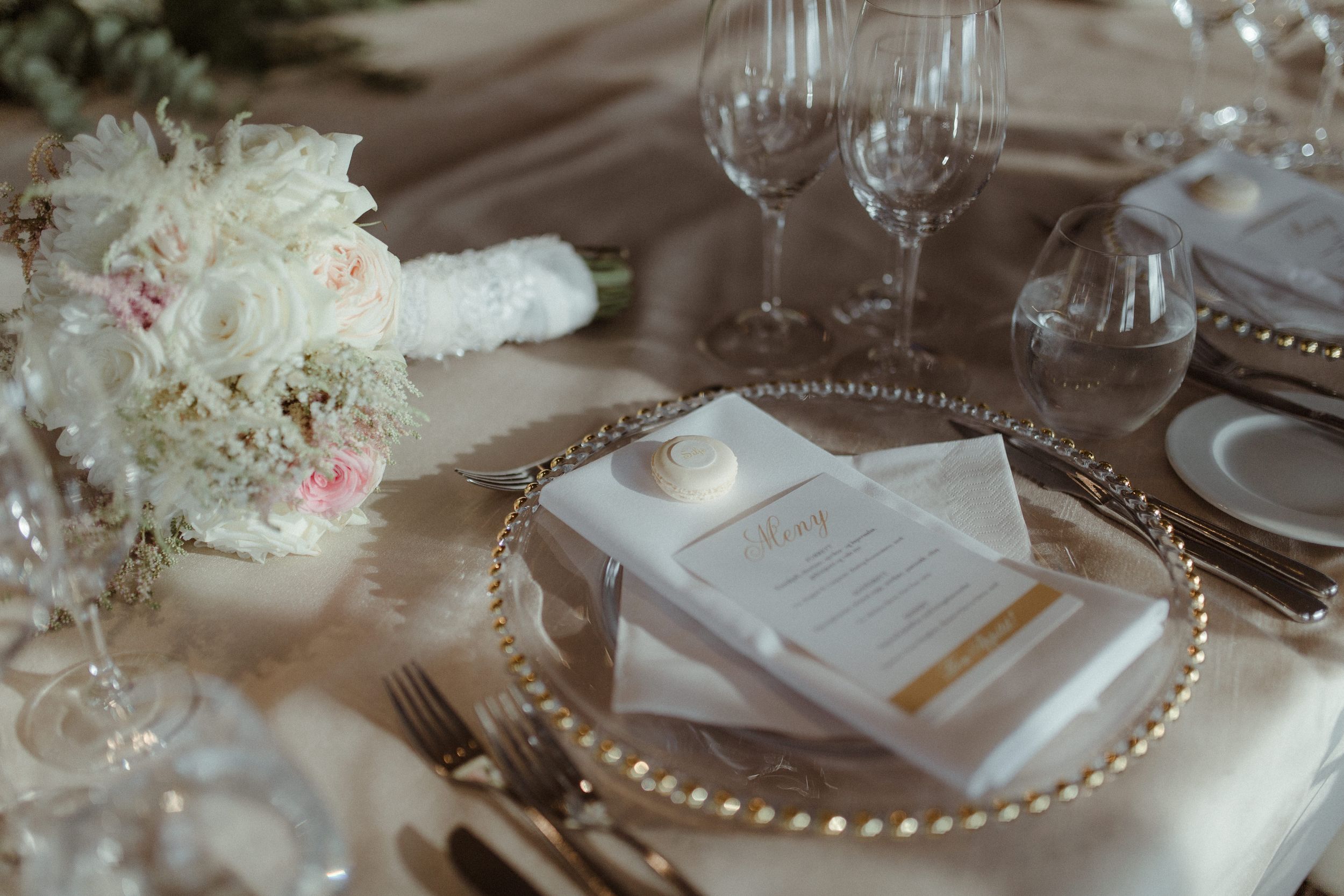 Wedding reception table decor featuring pearly beaded charger plates, crystal stemware and delicate floral arrangements.