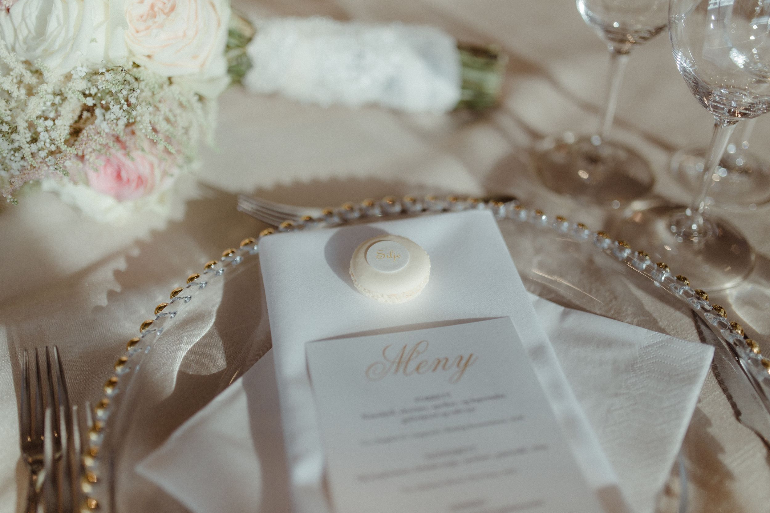 Close-up of wedding reception place settings with delicate menu cards and floral details.