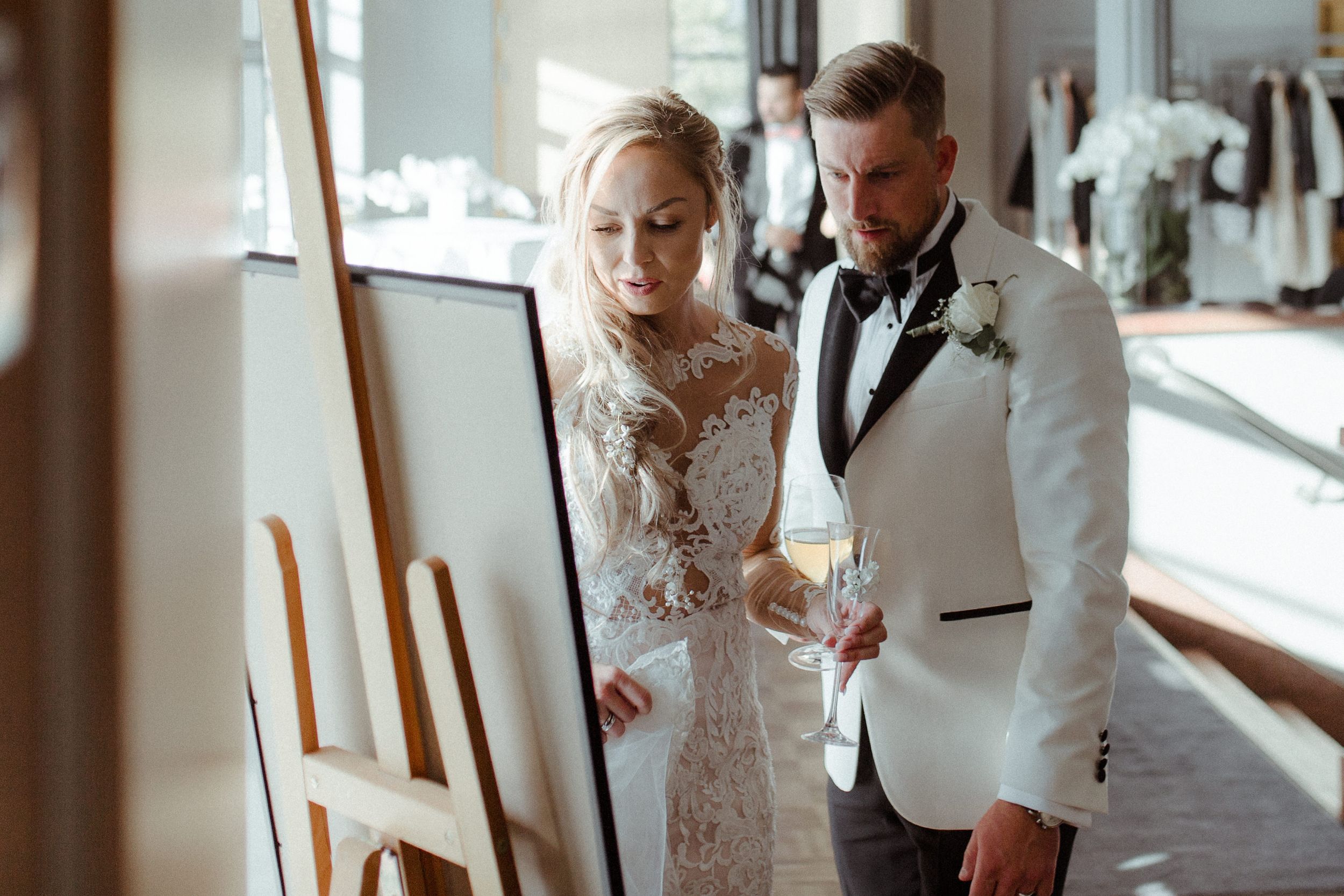 Wedding party gathered in an elegant indoor venue with white and formal attire.