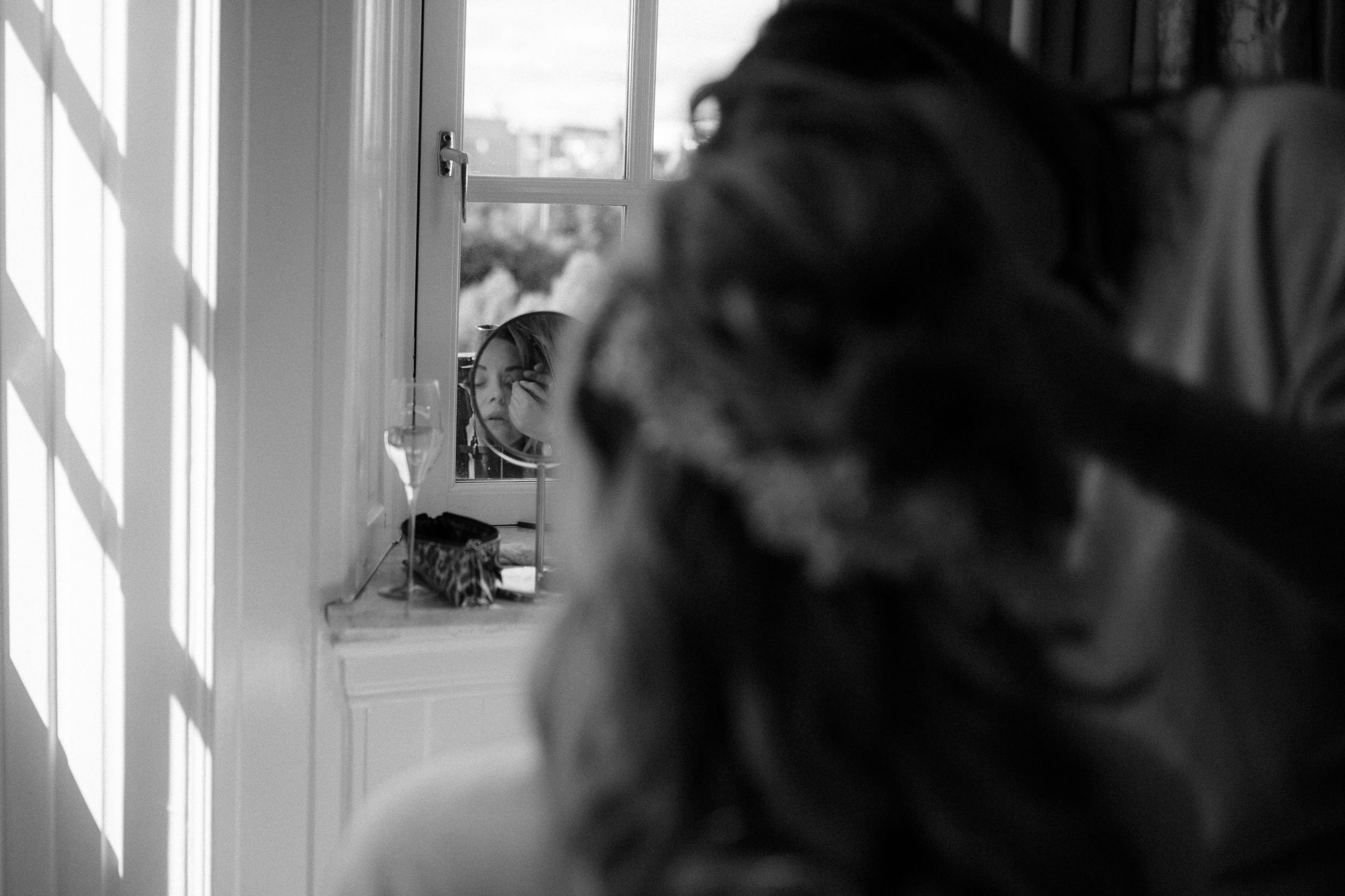 Black and white photo showing a silhouette against bright window blinds in a home interior.