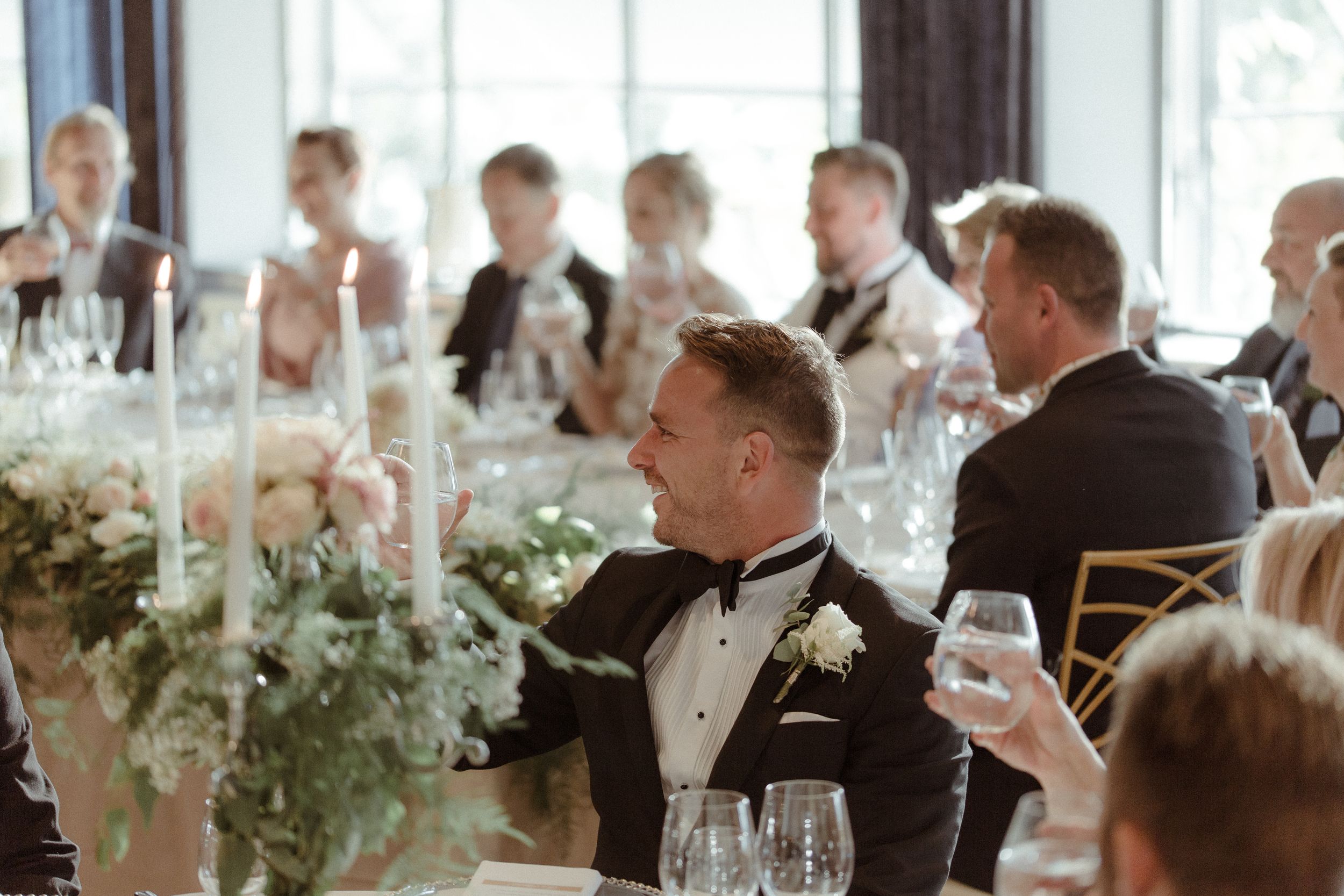 Wedding guests raise their glasses in celebration during an elegant reception dinner.