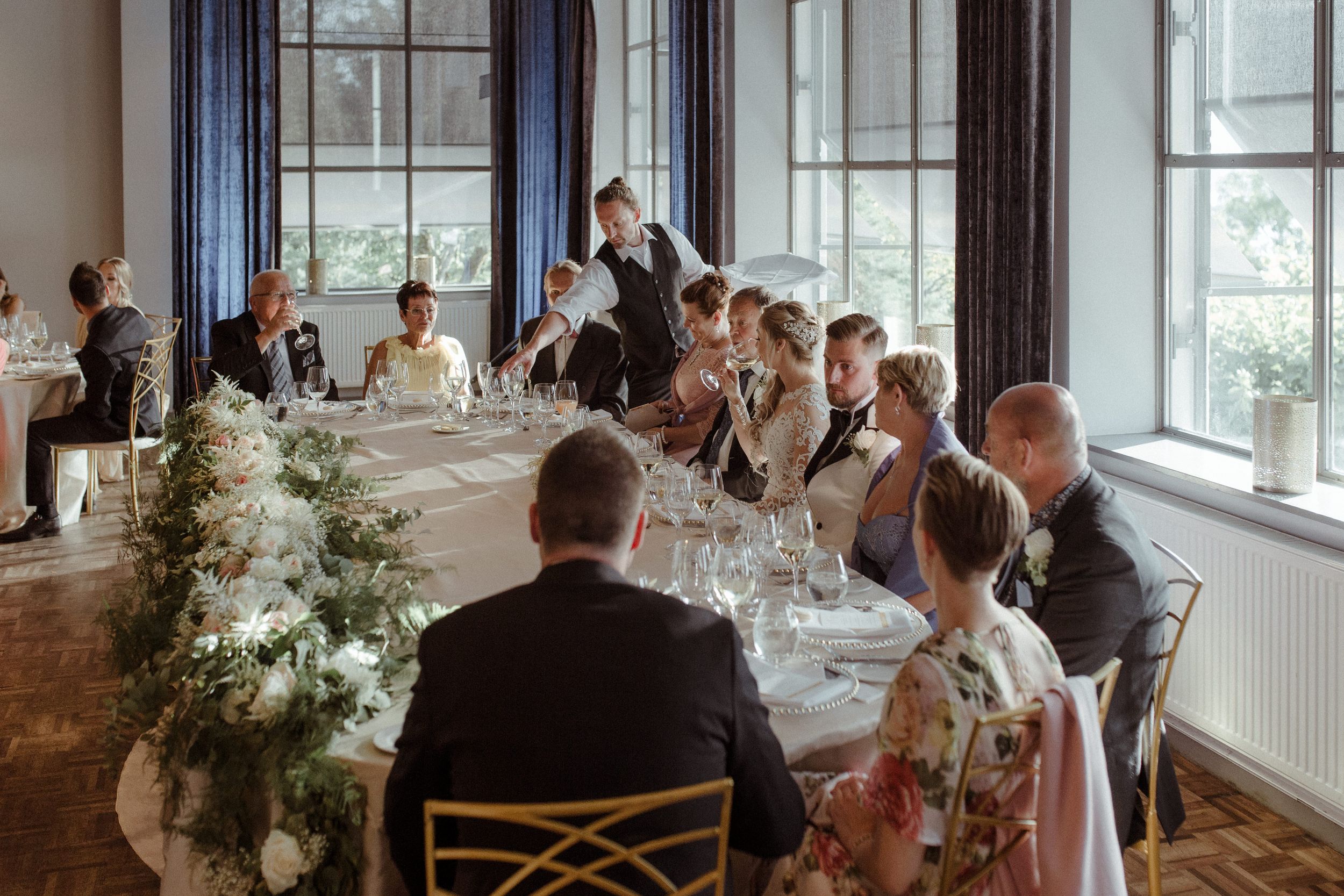 Bright sunlit room with large windows set up for an elegant wedding reception.