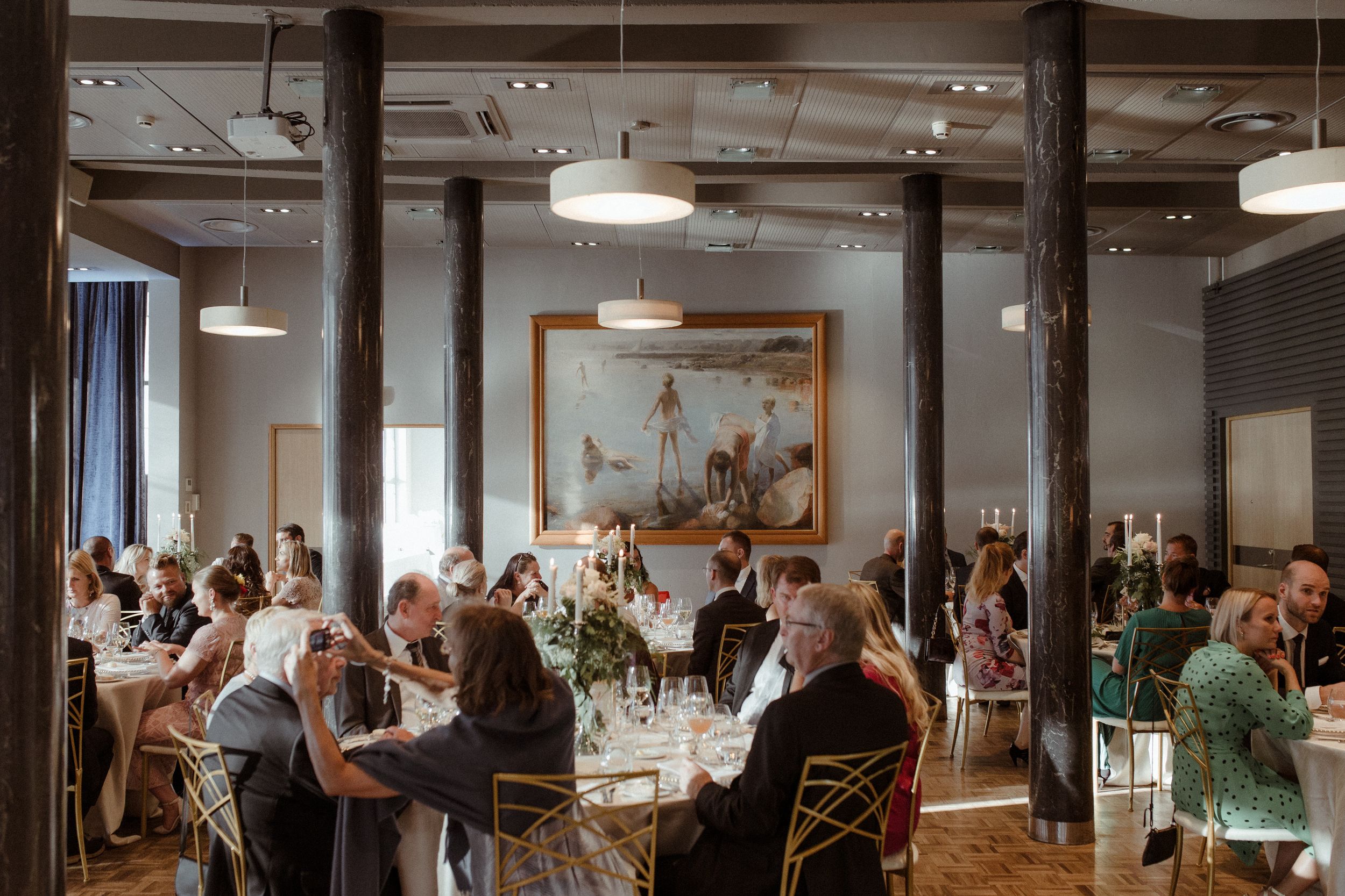 Interior of an industrial-style venue with exposed beams and pendant lighting during a celebration.