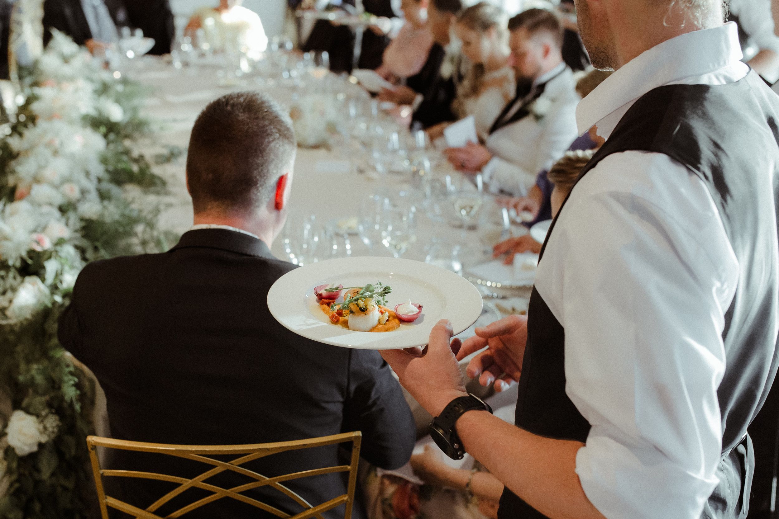 Guests enjoying a formal dinner service at an elegant indoor wedding reception.