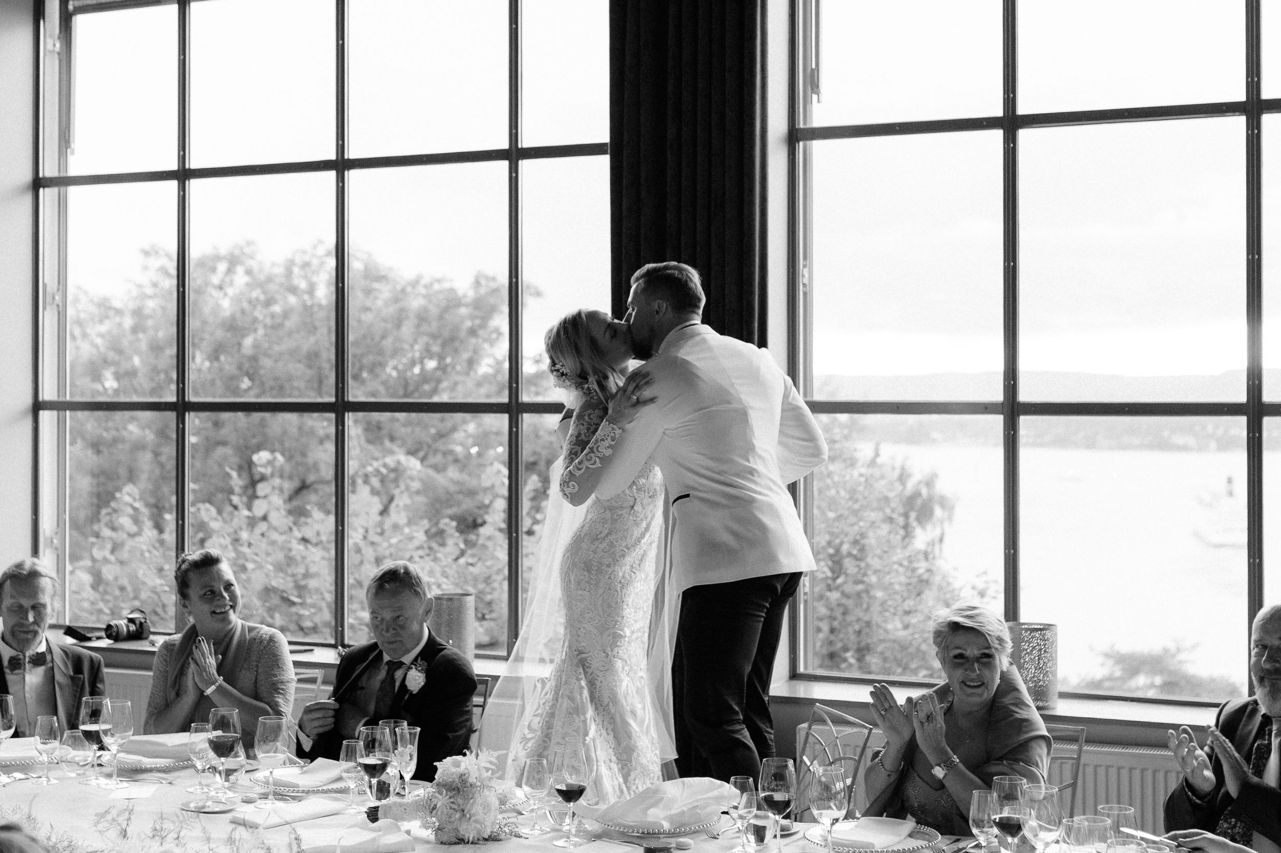 Large windows flood natural light into an elegant reception venue with dining tables.