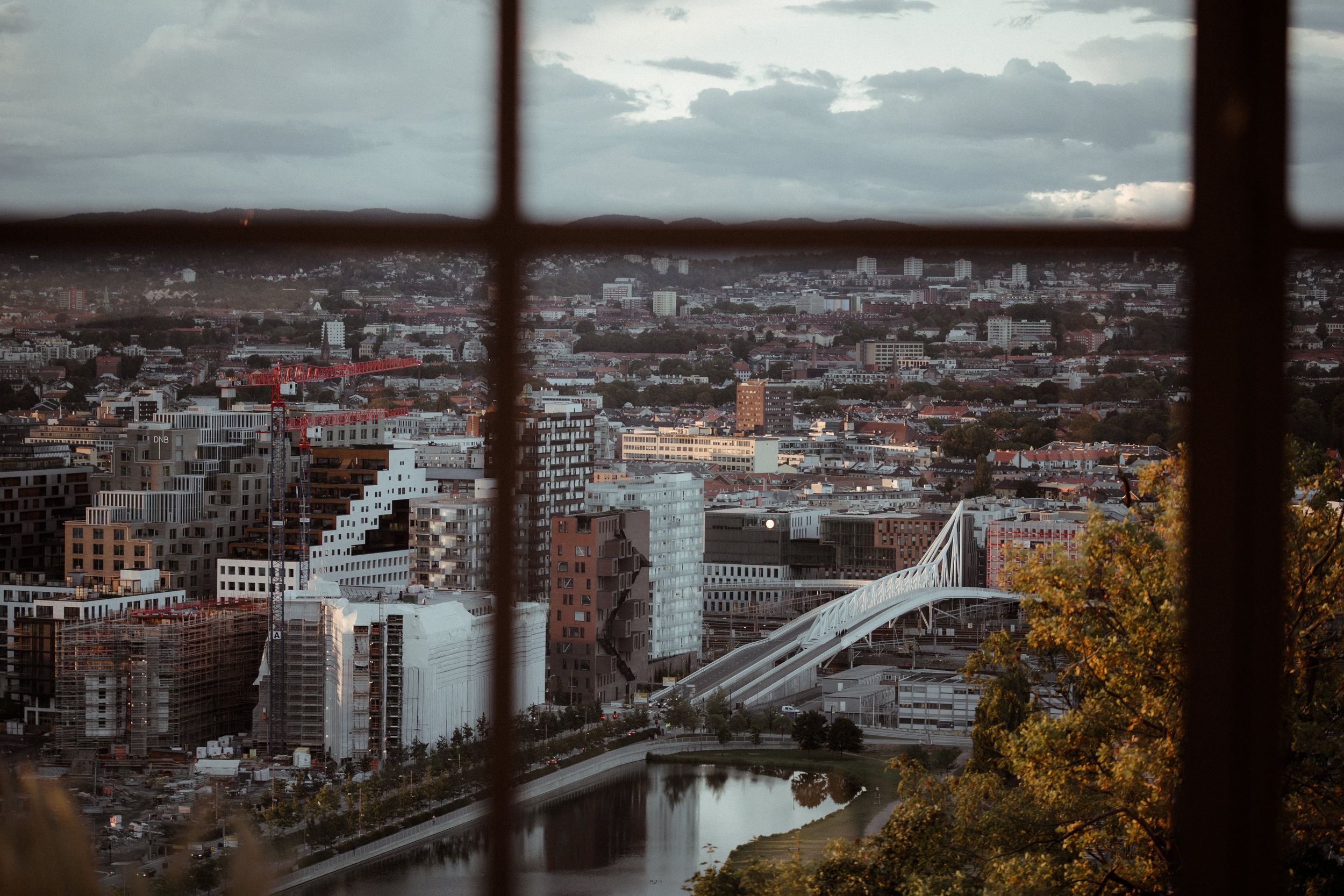 Panoramic cityscape view showing urban buildings and bridges under cloudy skies at dusk.