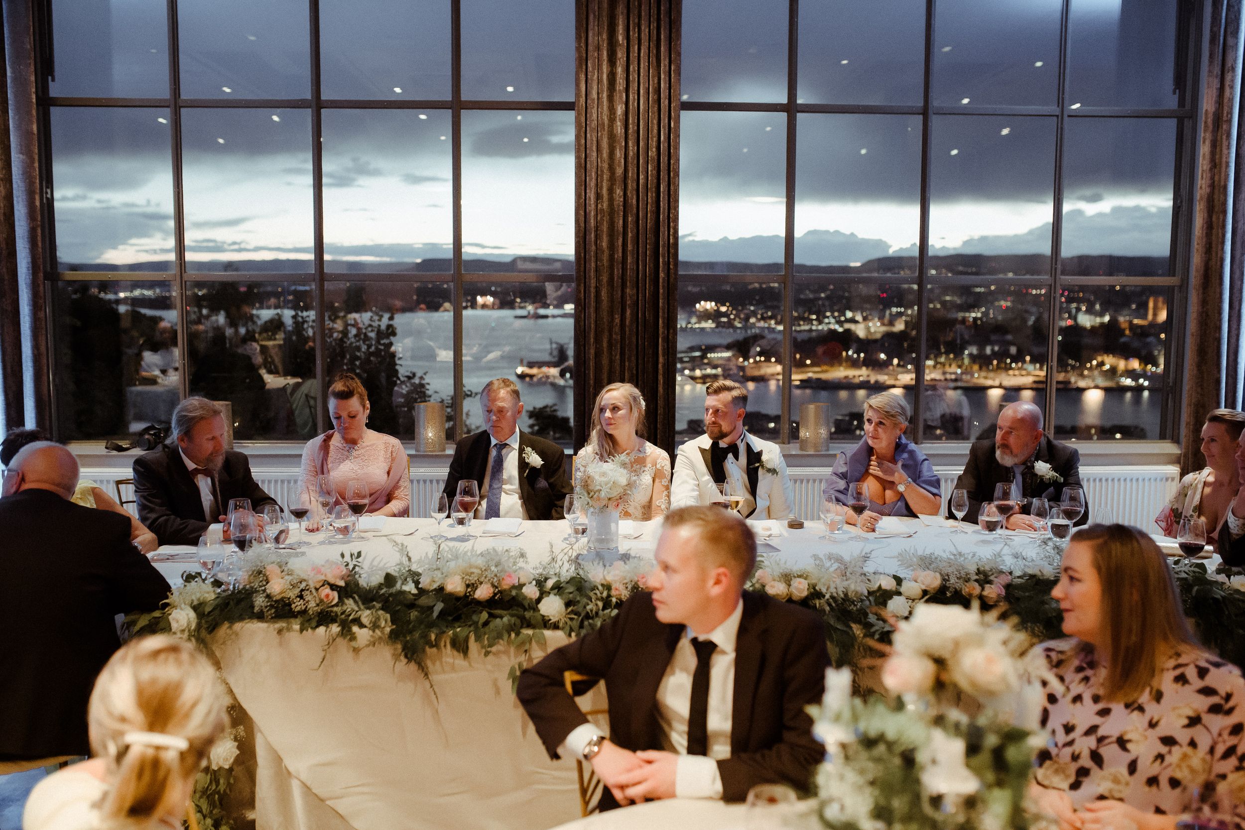 Wedding reception venue at night with panoramic city views and elegant table settings.