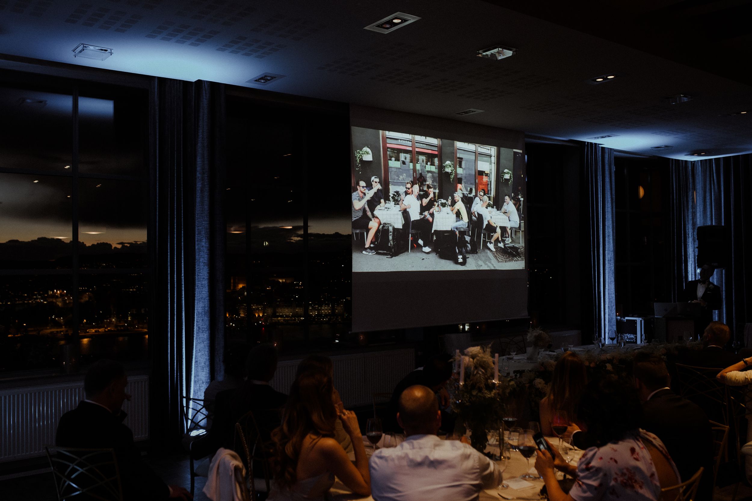 Dark reception room with projector screen and ambient lighting.