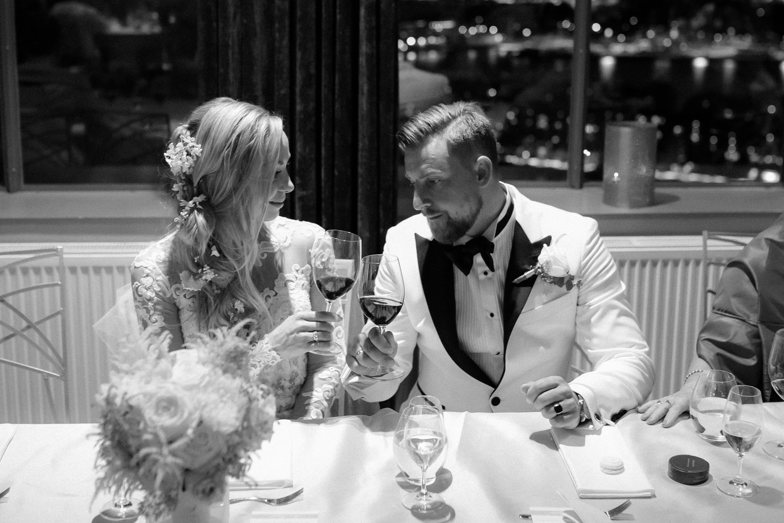 Wedding guests engaged in casual conversation around elegant dining tables at an indoor reception.