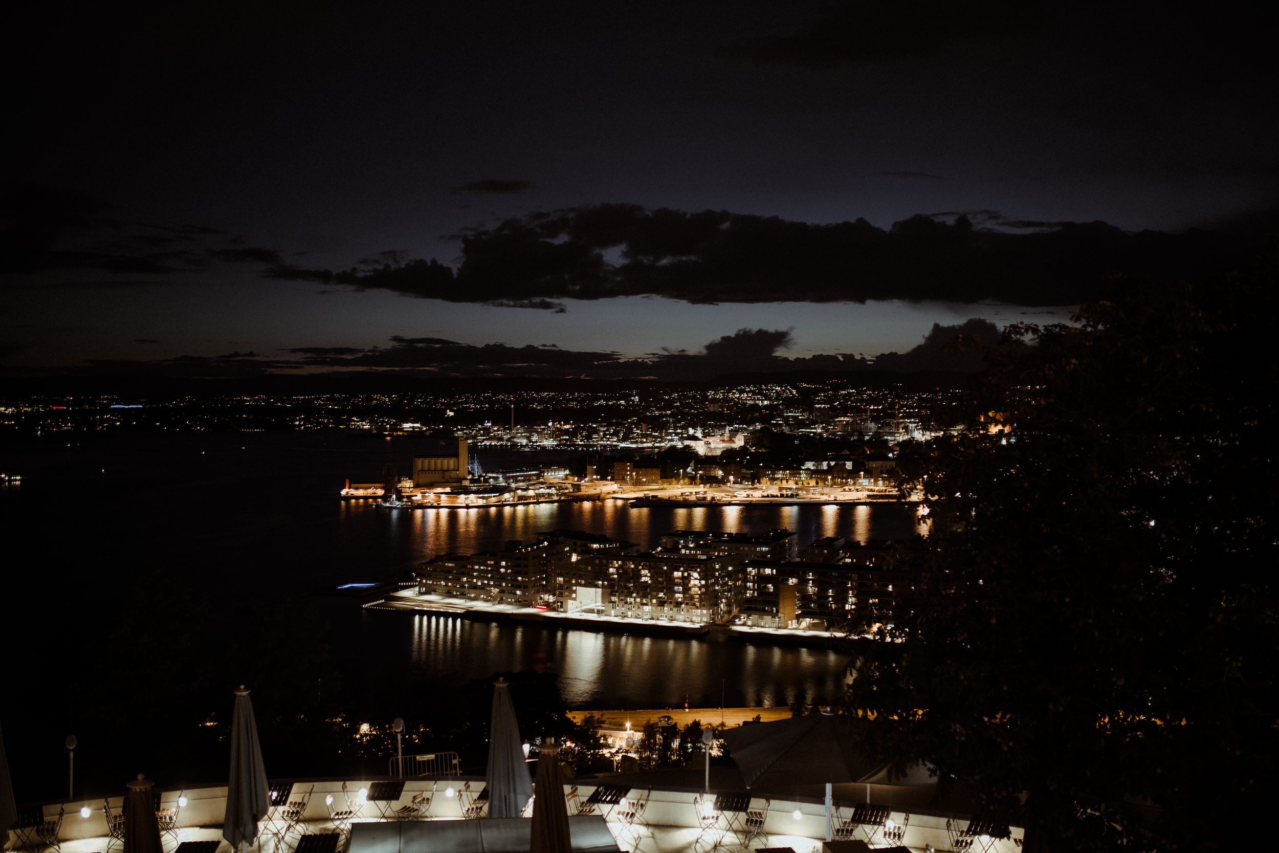 Scenic nighttime cityscape showing glowing lights reflecting on water.