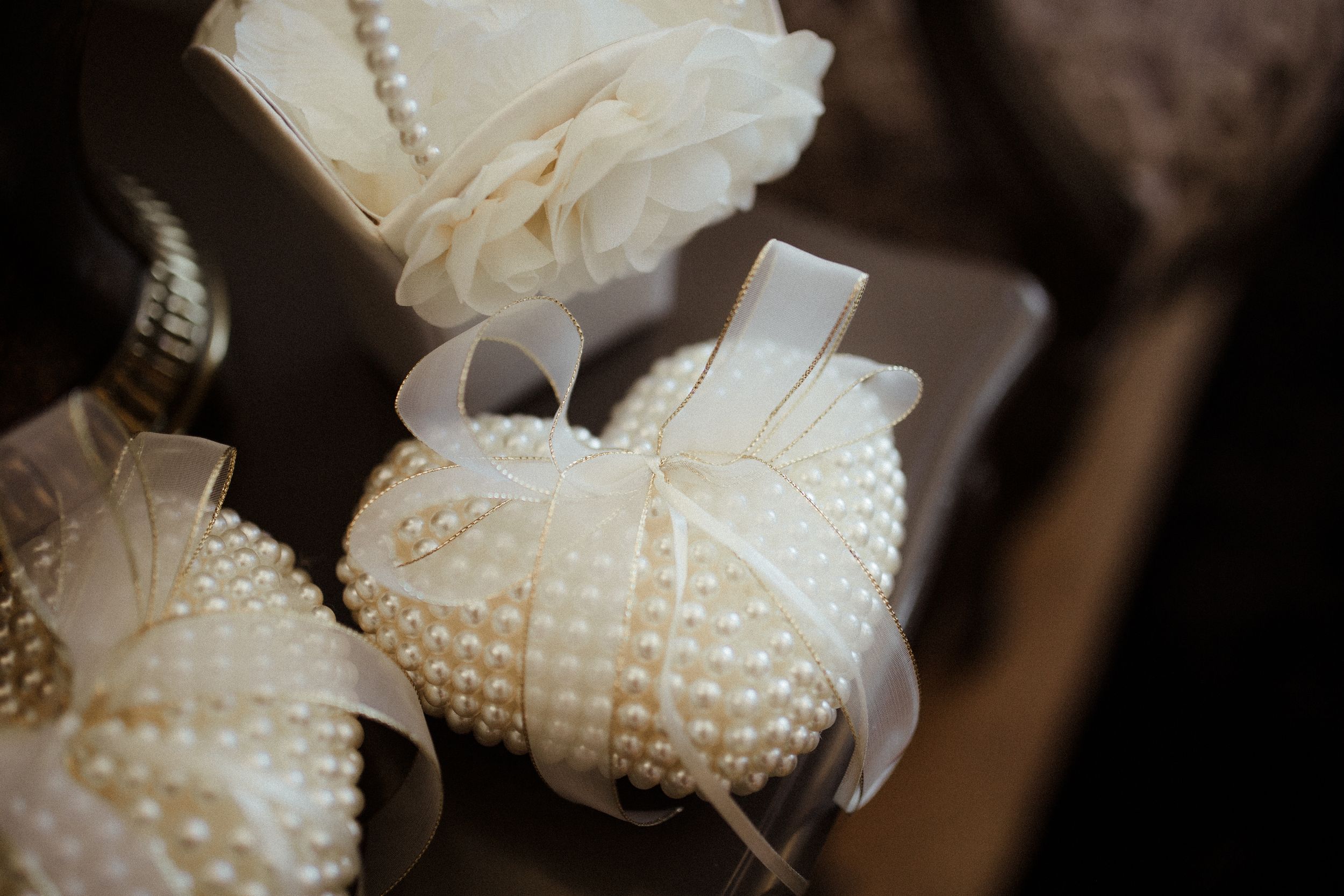 Close-up of delicate white pearl wedding accessories on dark background.