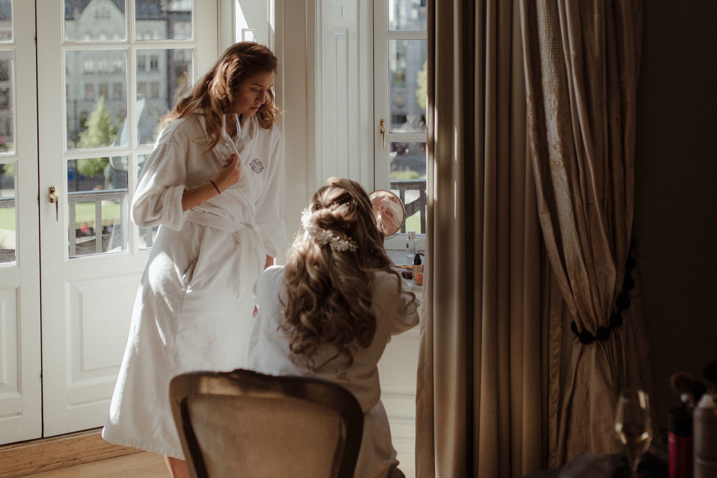 Light streams through elegant windows onto a white veil and dress during wedding day preparations.