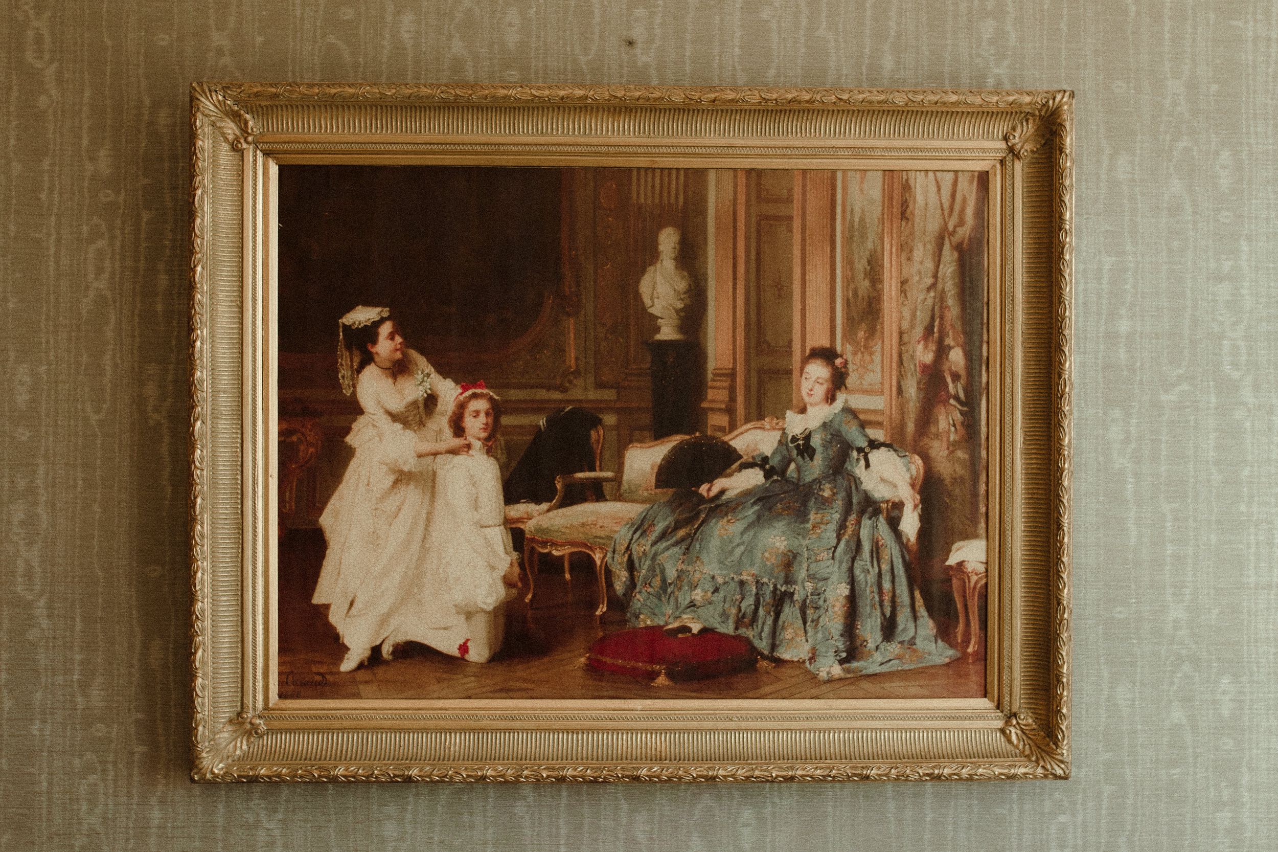 A series of vintage-style oil paintings in ornate gold frames displayed on a neutral wall.