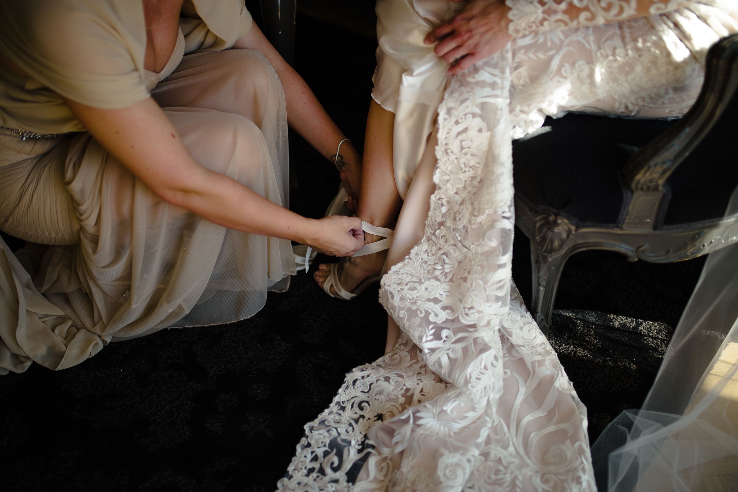 Detail shots of hands adjusting and smoothing a delicate white lace wedding dress.