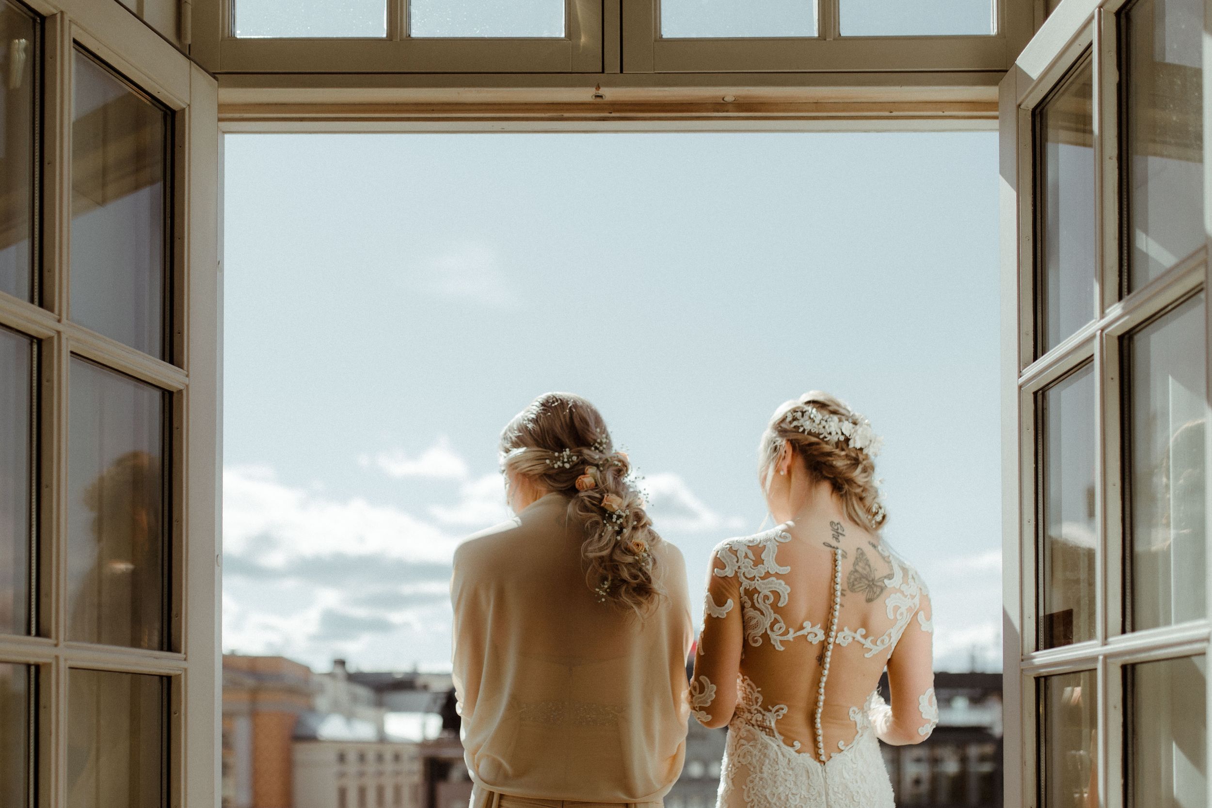 Light streams through large windows in an elegant white room with ornate architectural details.
