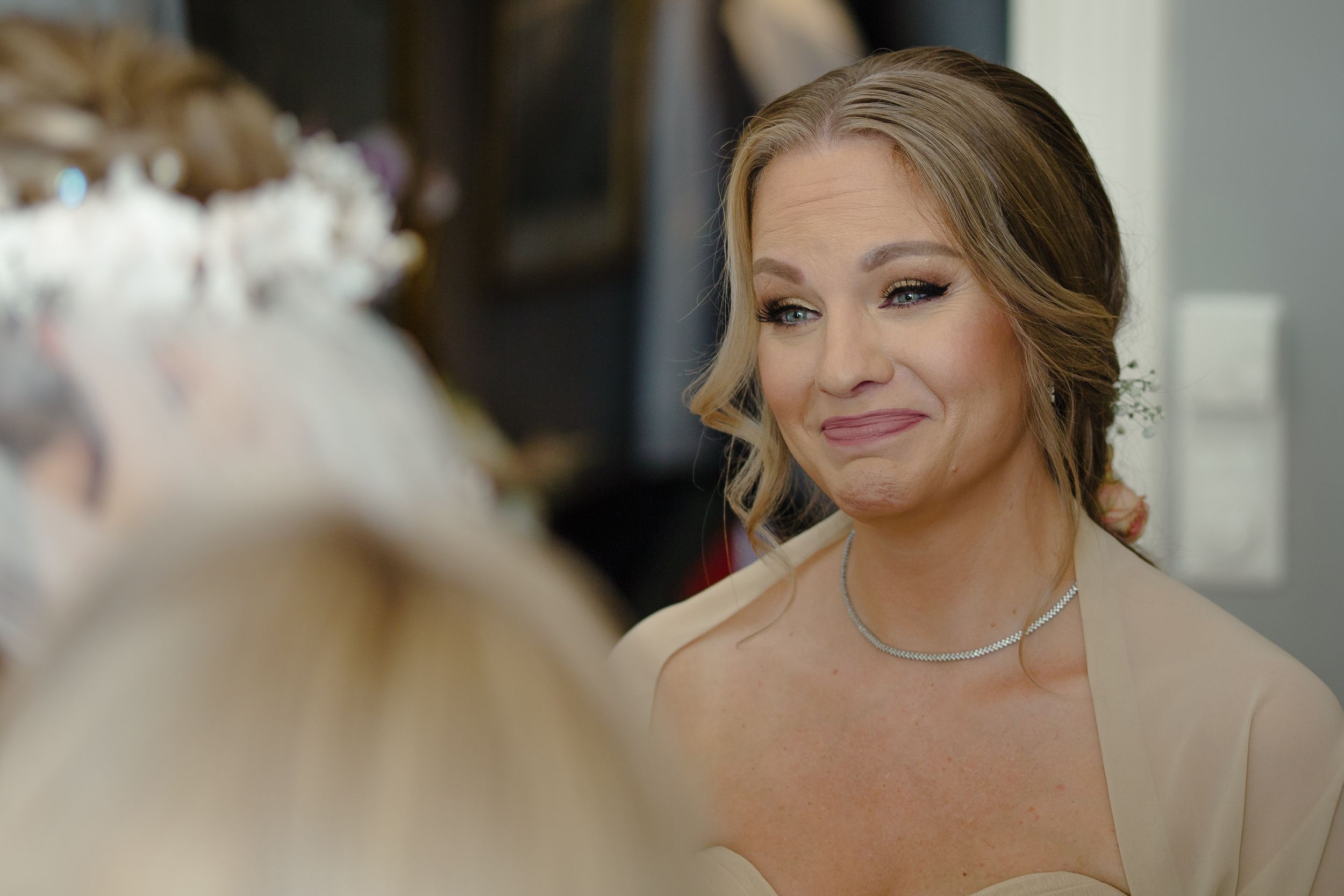 Bride getting ready in morning light while looking at her reflection.