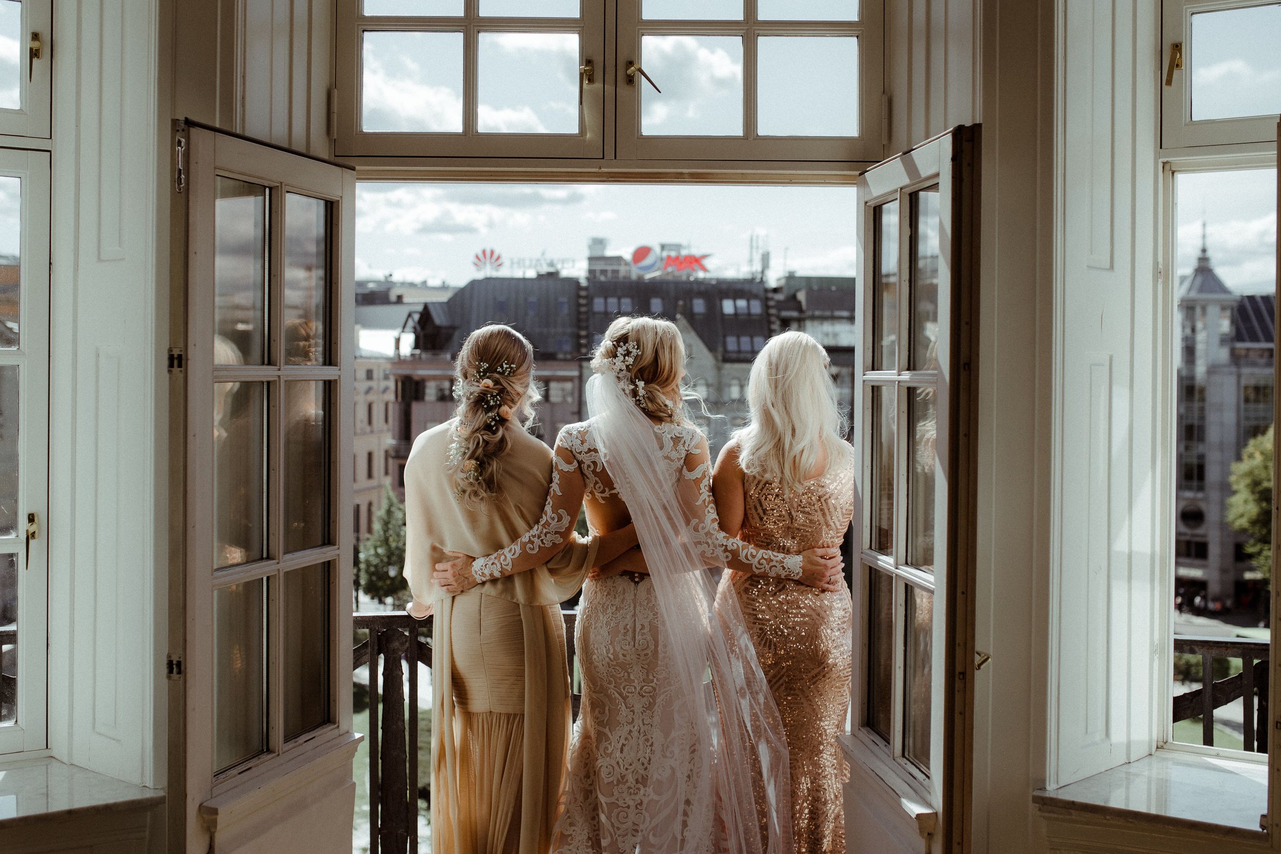 Elegant wedding venue interior with large windows and bridesmaids in neutral dresses.