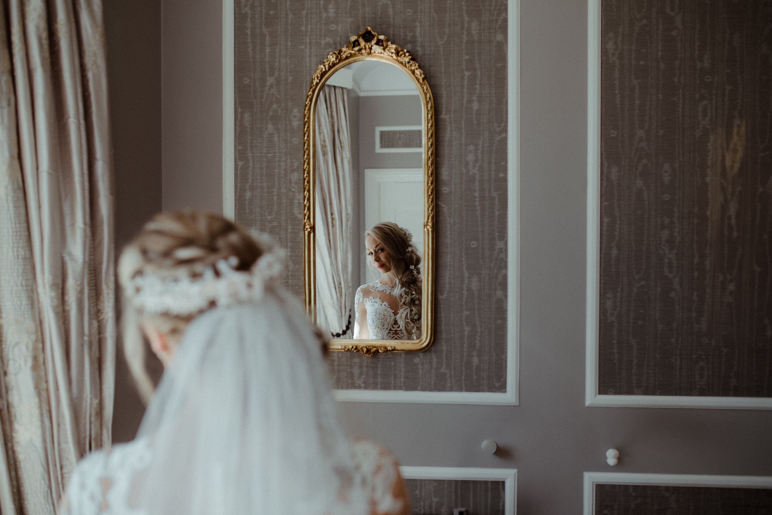 A wedding venue interior showcasing elegant wallpaper and ornate decorative mirrors.