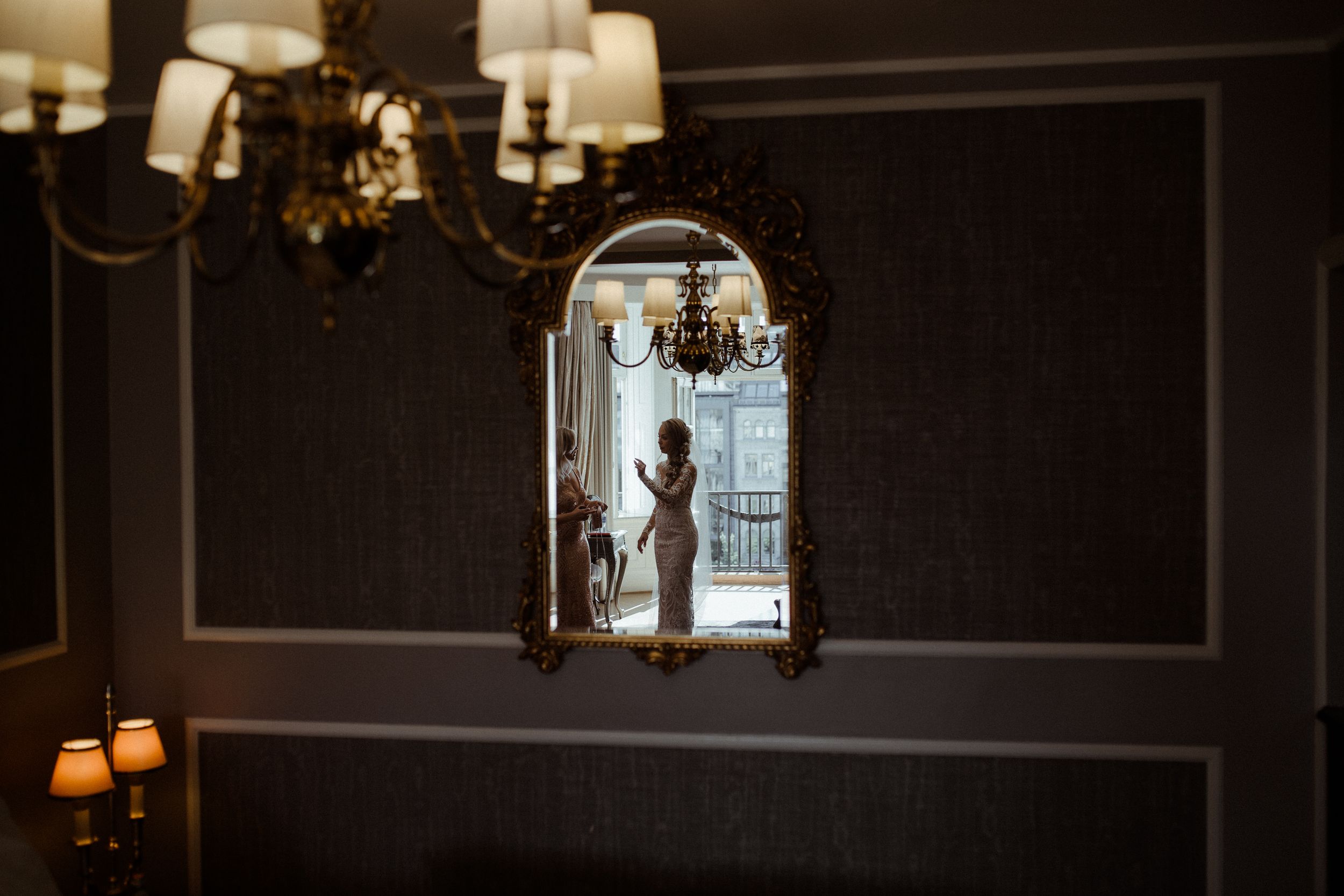 Silhouette reflected in vintage mirror with chandelier lighting in dark elegant room.