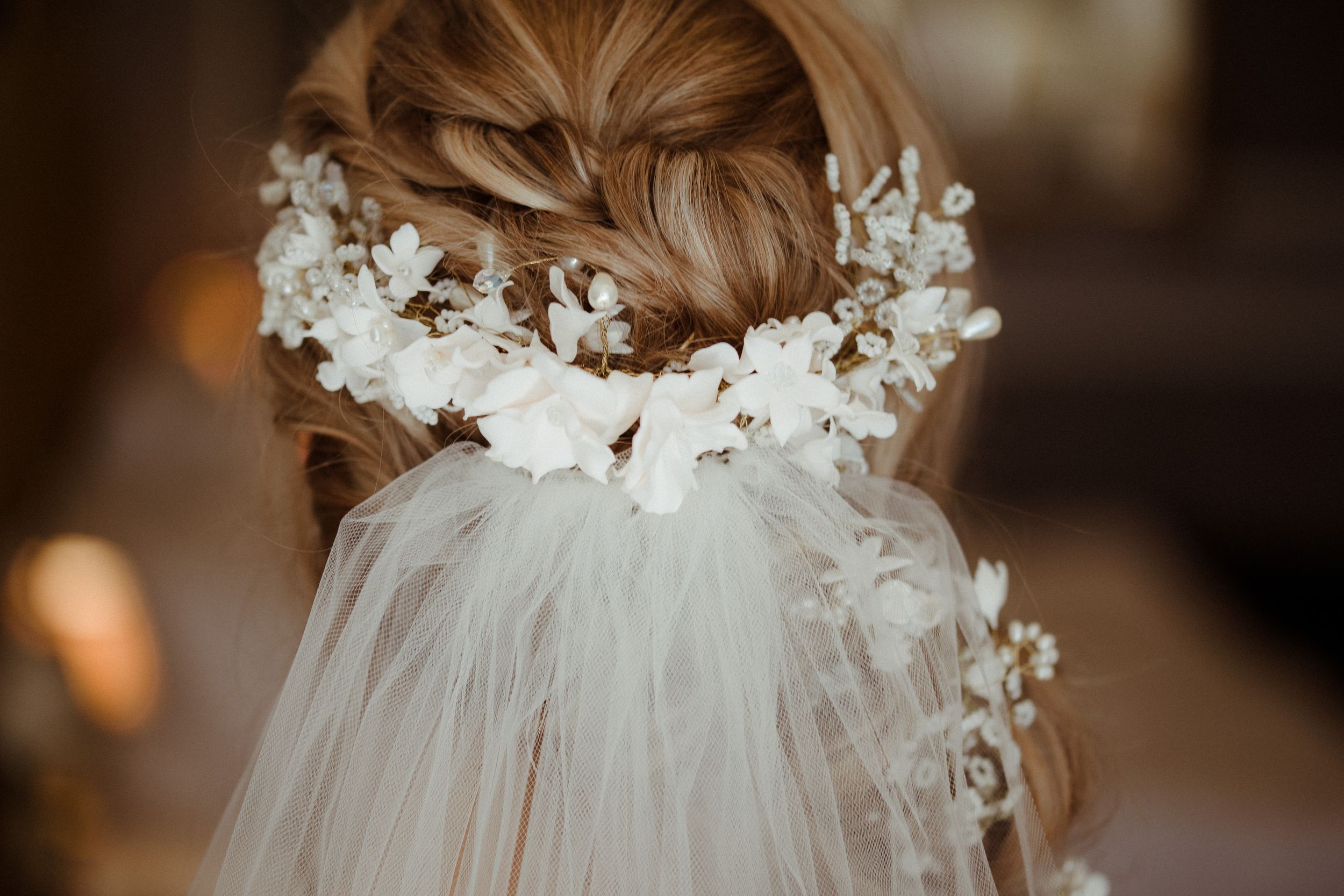 Close-up of bridal hair accessory featuring white floral details and flowing veil.