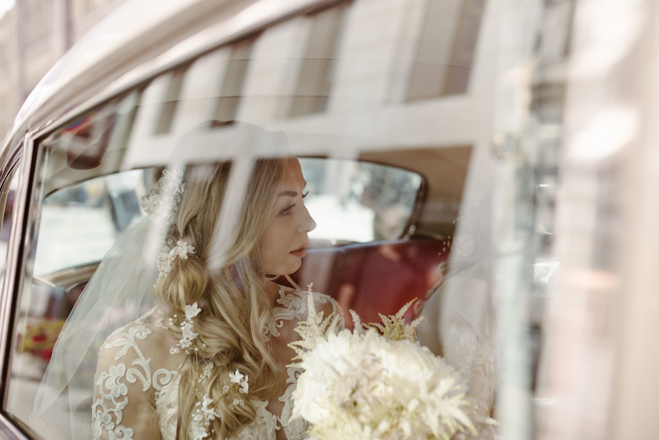 View through car window of elegant bridal details and white bouquet.