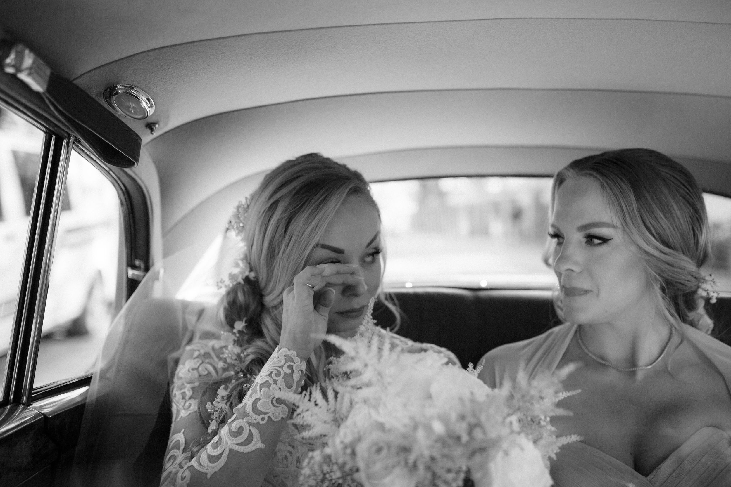 Wedding party sharing joyful moments and laughter inside a classic car during transportation.