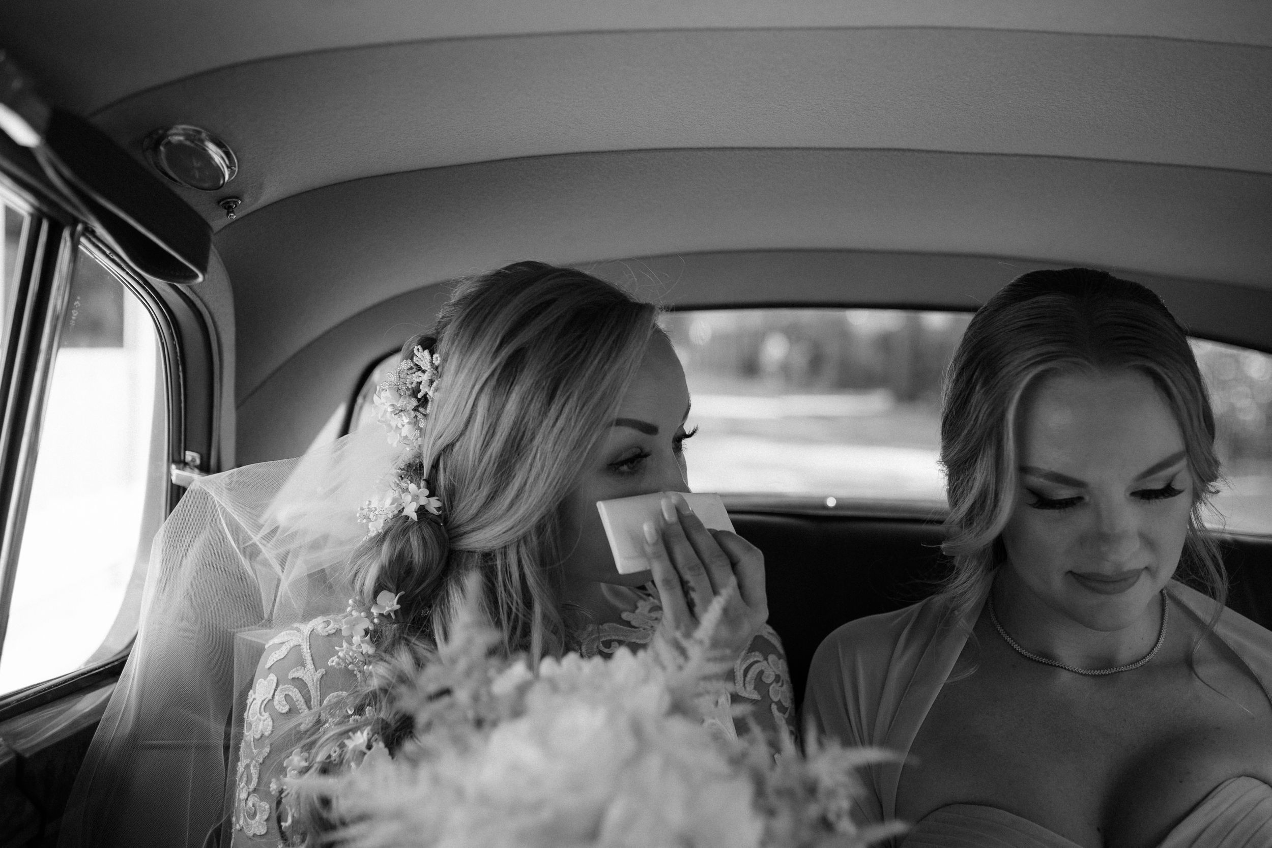 Black and white photograph capturing a tender moment through a car window.