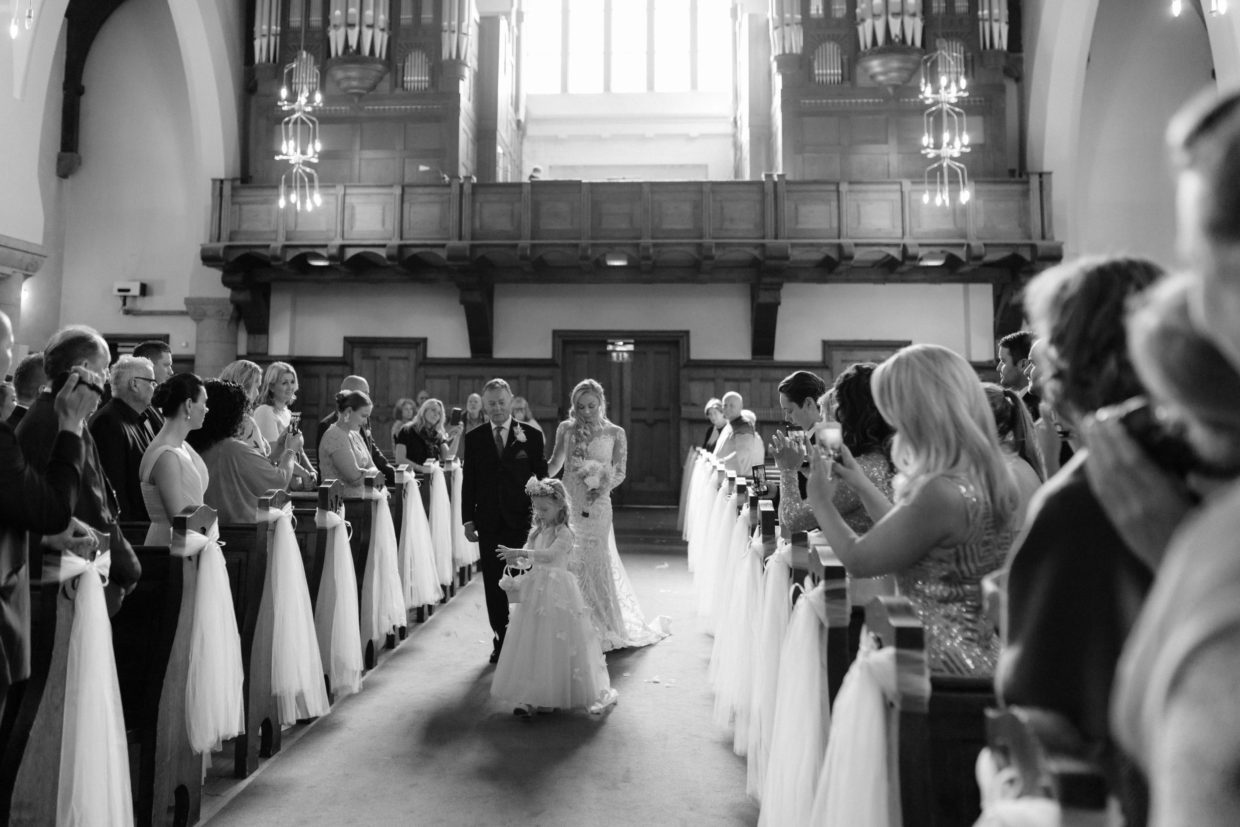Wedding ceremony venue with rows of white-decorated pews leading to the altar.