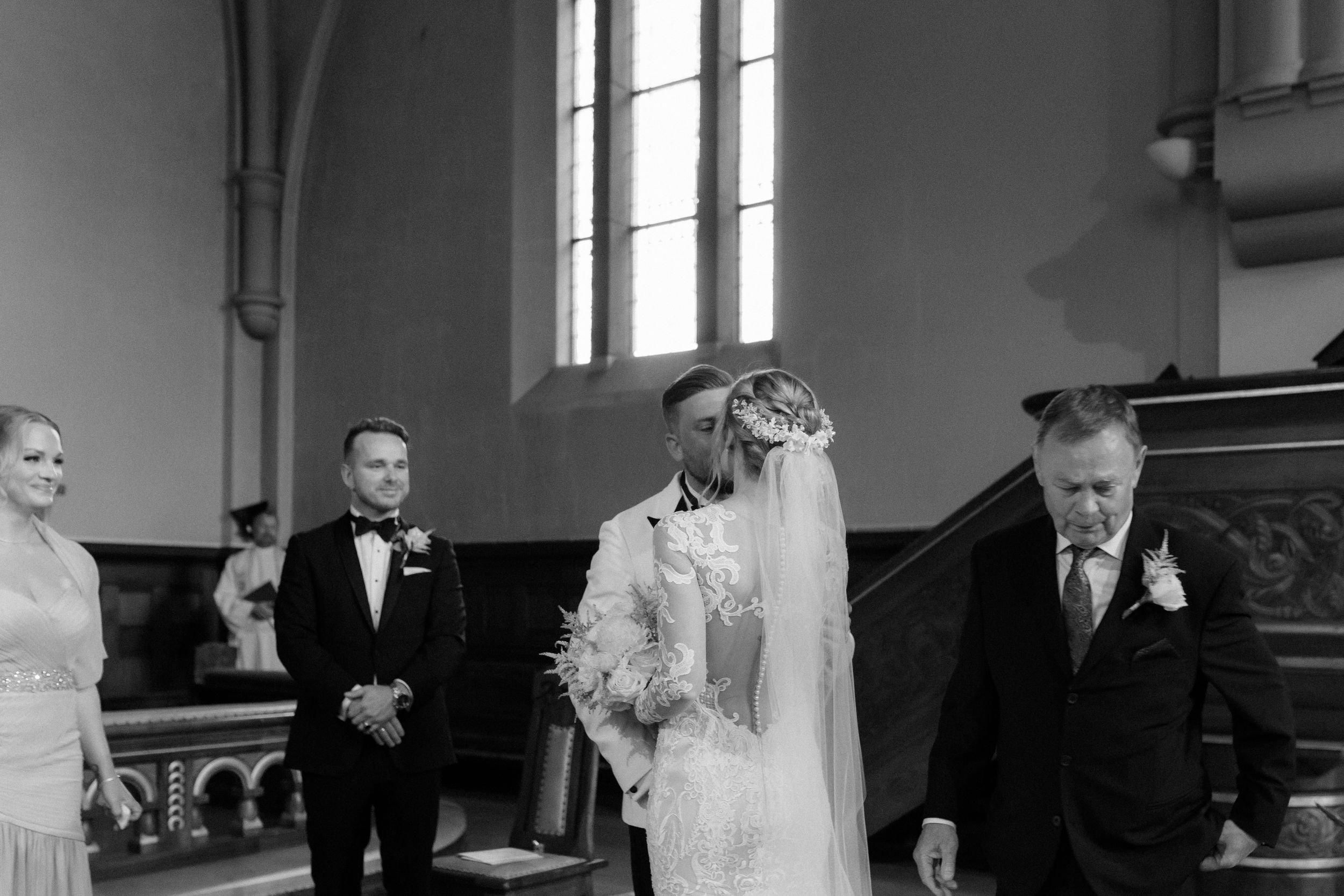A couple embraces during their wedding ceremony inside a grand church with ornate architectural details.