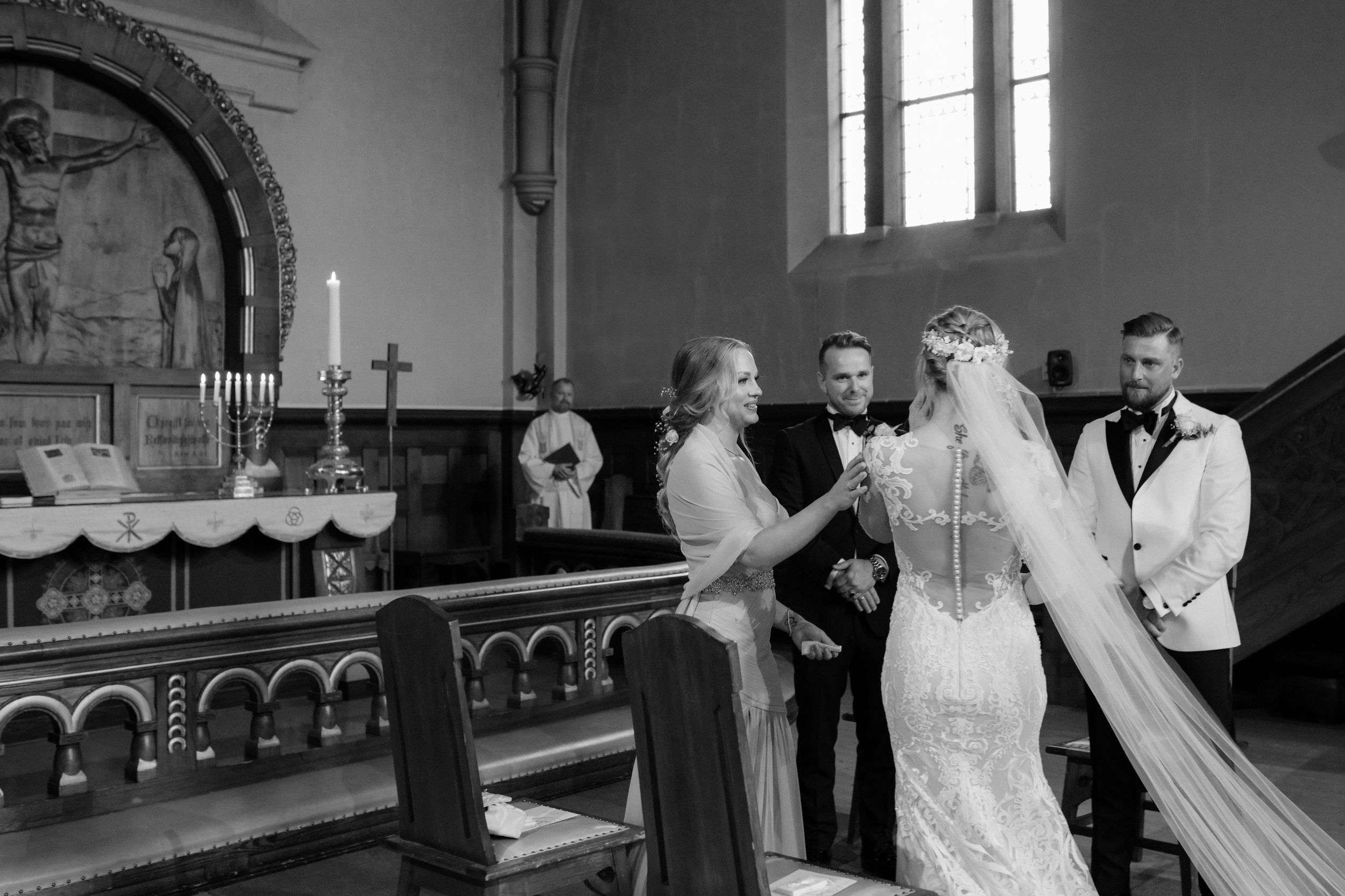 Traditional church interior with elaborate woodwork and arched windows during a wedding ceremony.