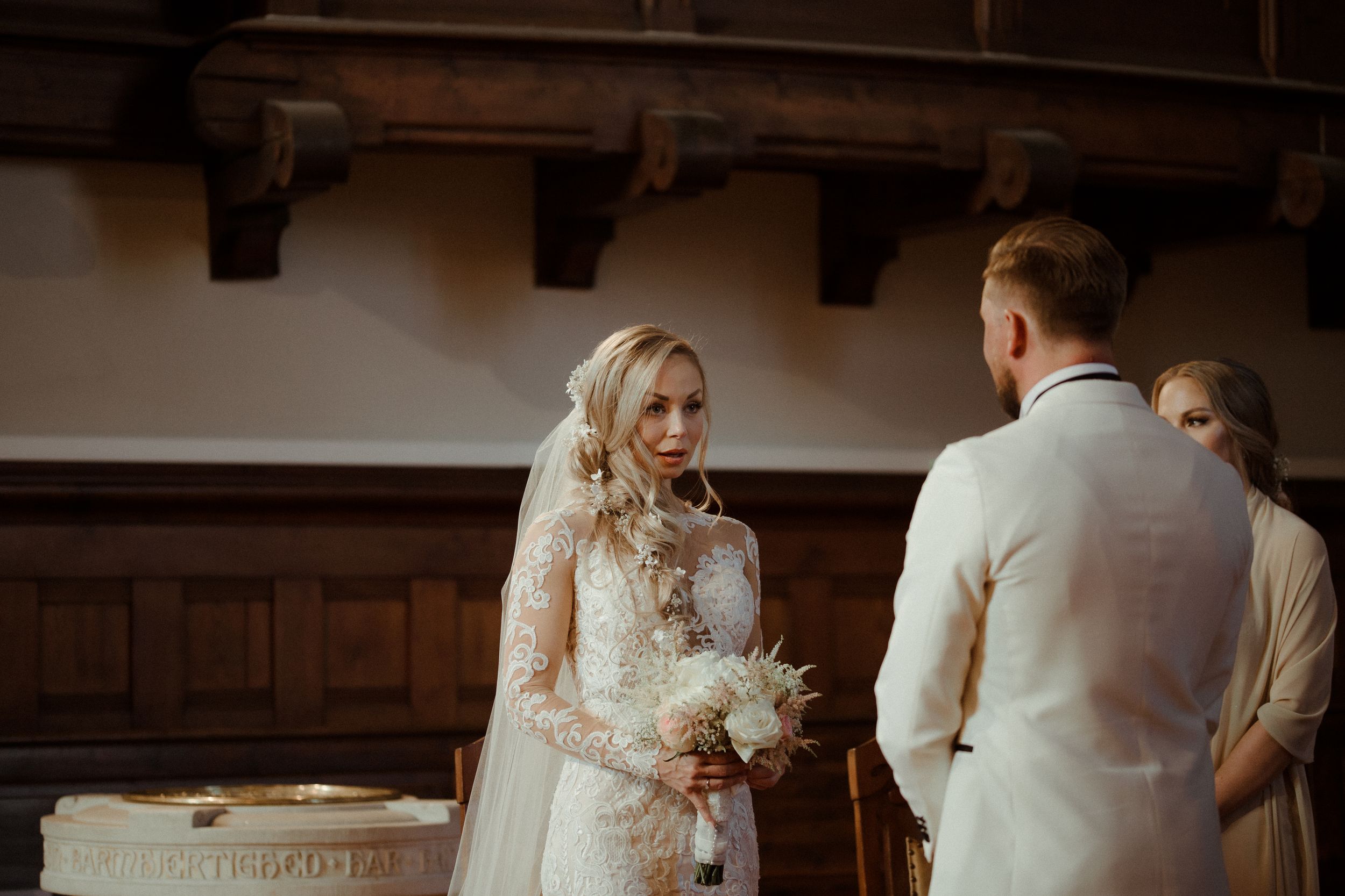 Couple walking down church aisle during wedding ceremony with guests watching from wooden pews.