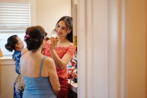 Three people in colorful dresses gather in a sunlit room during pre-event preparations.