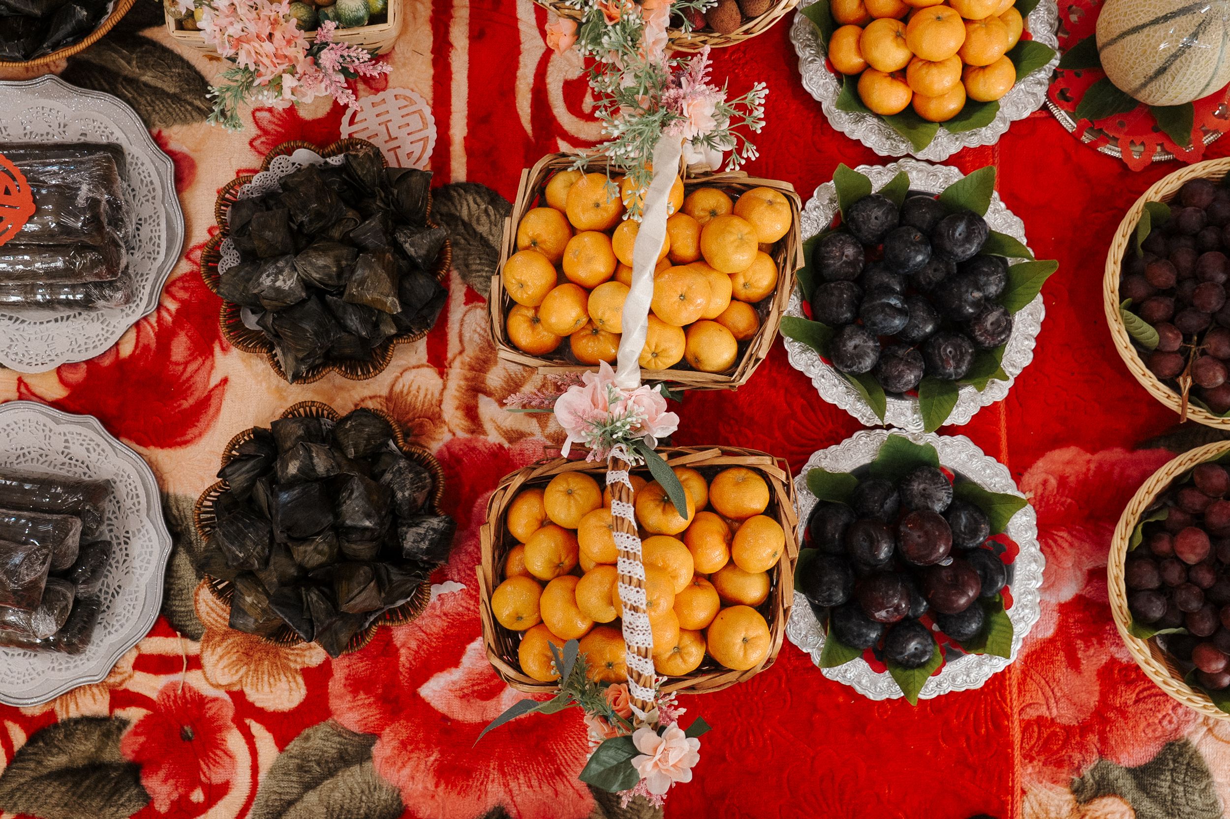 Overhead view of colorful Chinese Lunar New Year snacks and treats arranged on a red tablecloth.