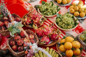 Fresh seasonal fruits and vegetables arranged at an outdoor market with colorful grapes, oranges and produce displays.