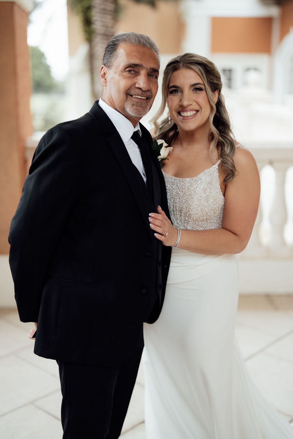 Emotional wedding first look moment under covered colonnade with decorative columns.