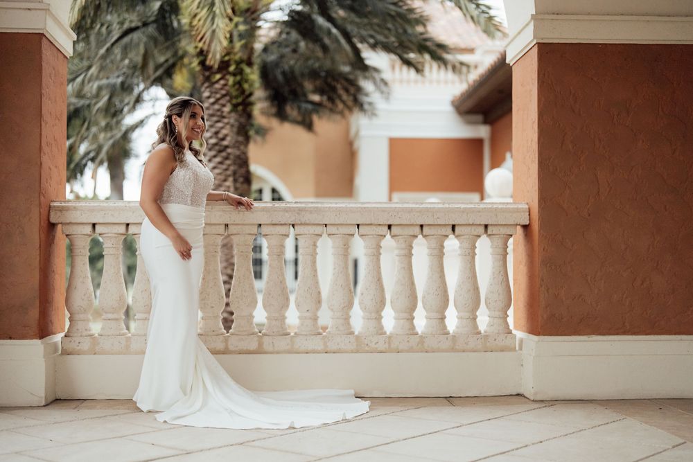 Elegant white balustrade walkway with palm trees creates a romantic Mediterranean wedding venue setting.