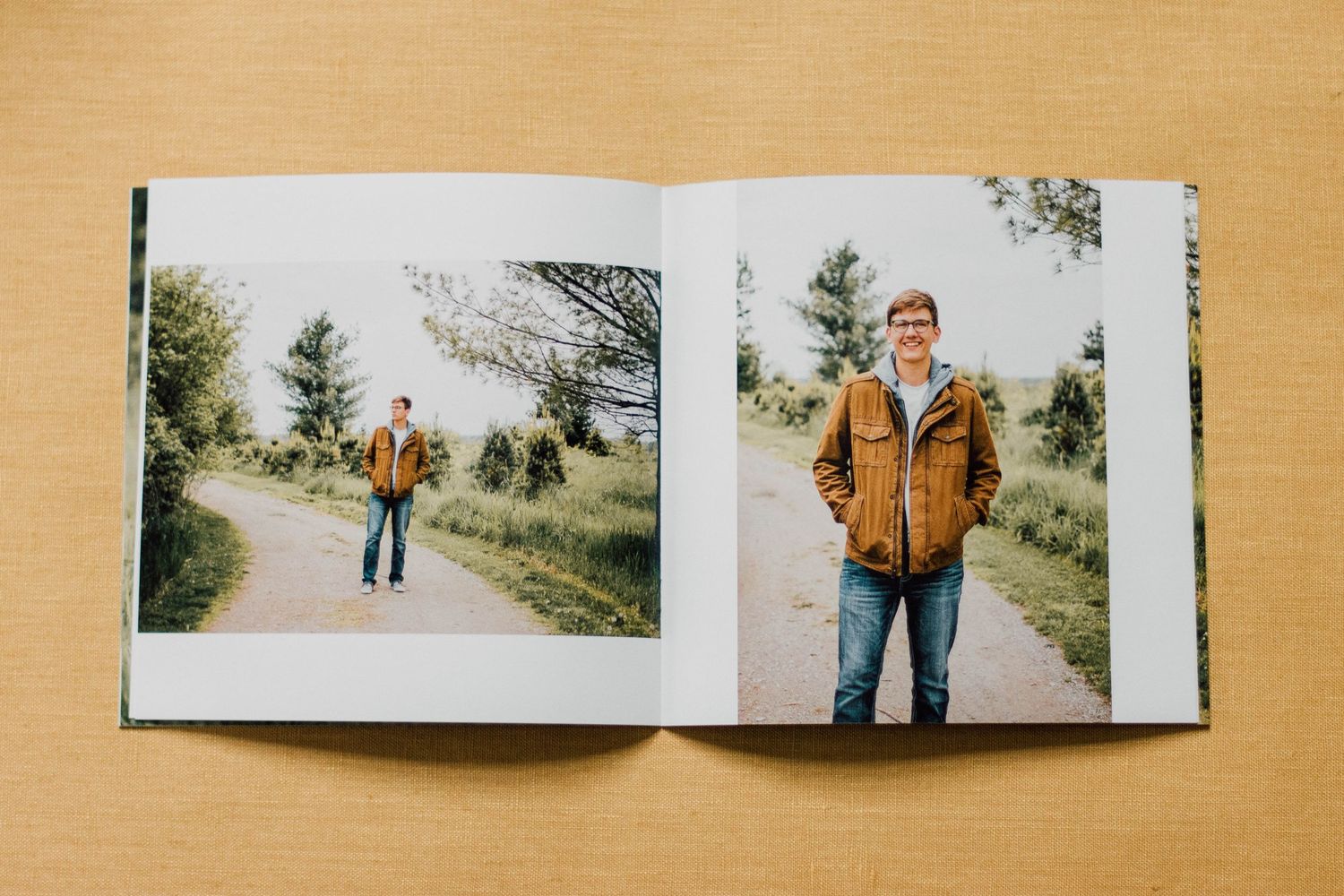 Open photo book displaying outdoor portrait session spreads on wooden surface.
