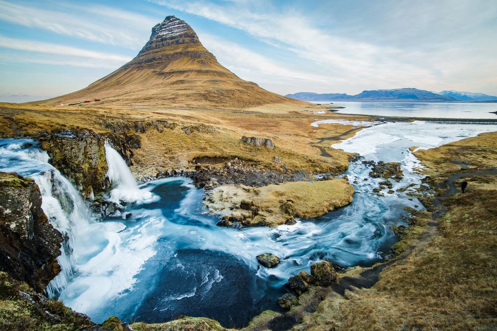 A dramatic panoramic view of the rugged Faroe Islands coastline with steep cliffs and turquoise ocean waters below.