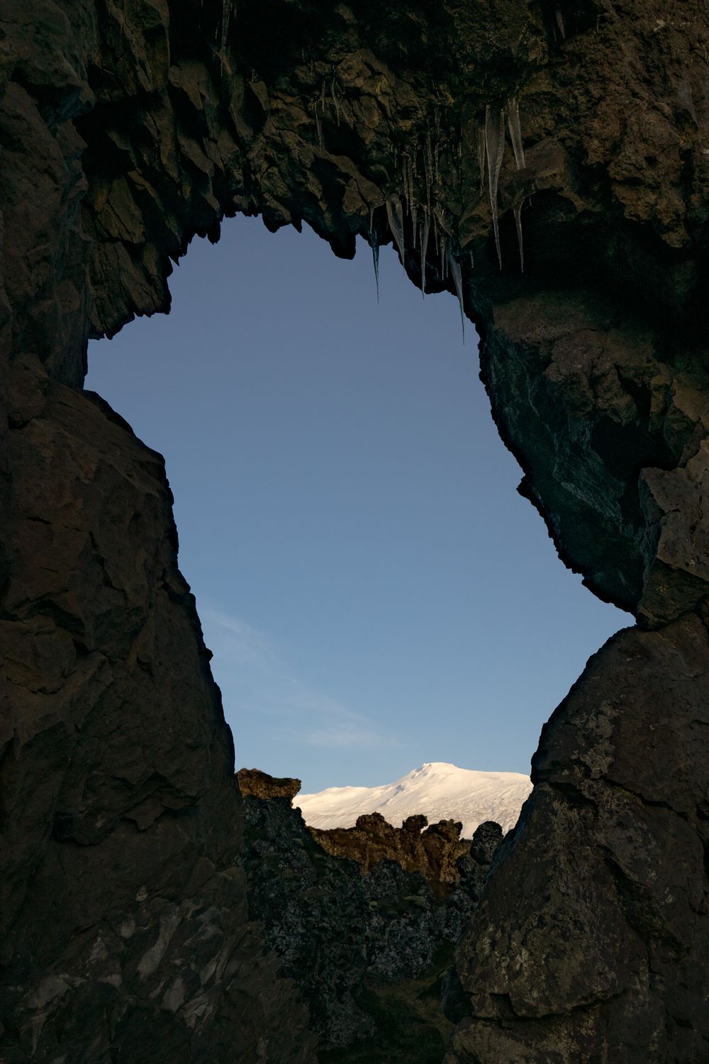Four connected natural rock archways frame views of a blue sky and distant mountains in the desert wilderness.