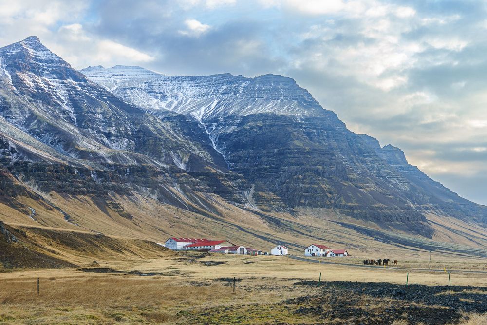 Panoramic view of a snowy mountain range with red roofed buildings nestled in the valley below.