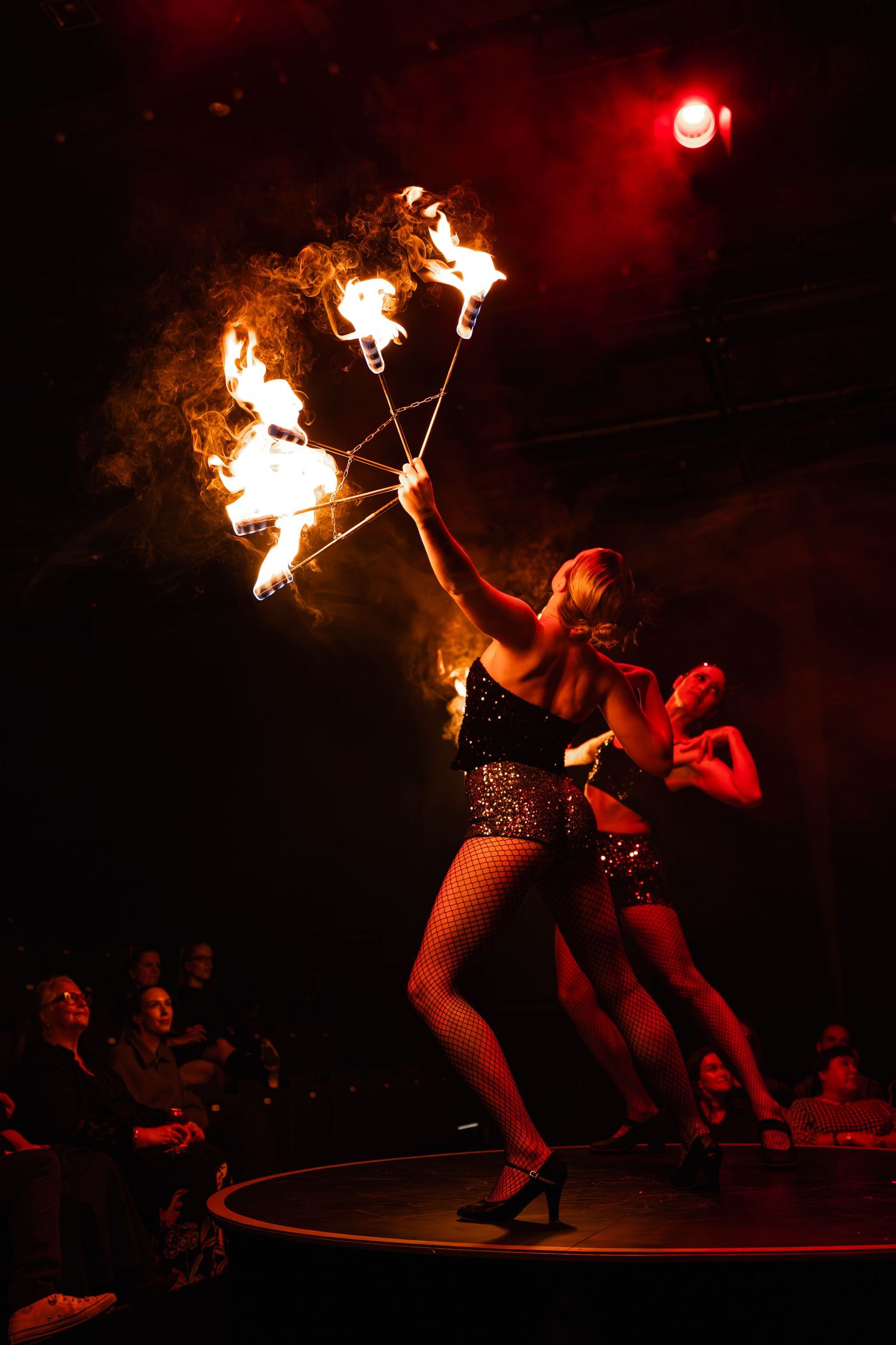 Performers on stage bathed in dramatic red lighting strike dynamic poses during a dance performance.
