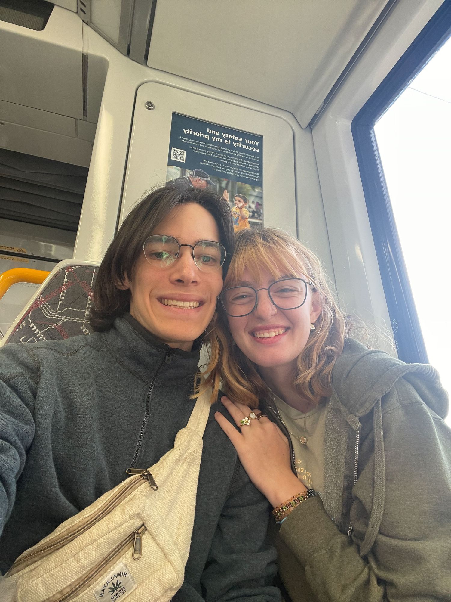 Two people sit close together and smile while taking a series of selfies on public transportation.