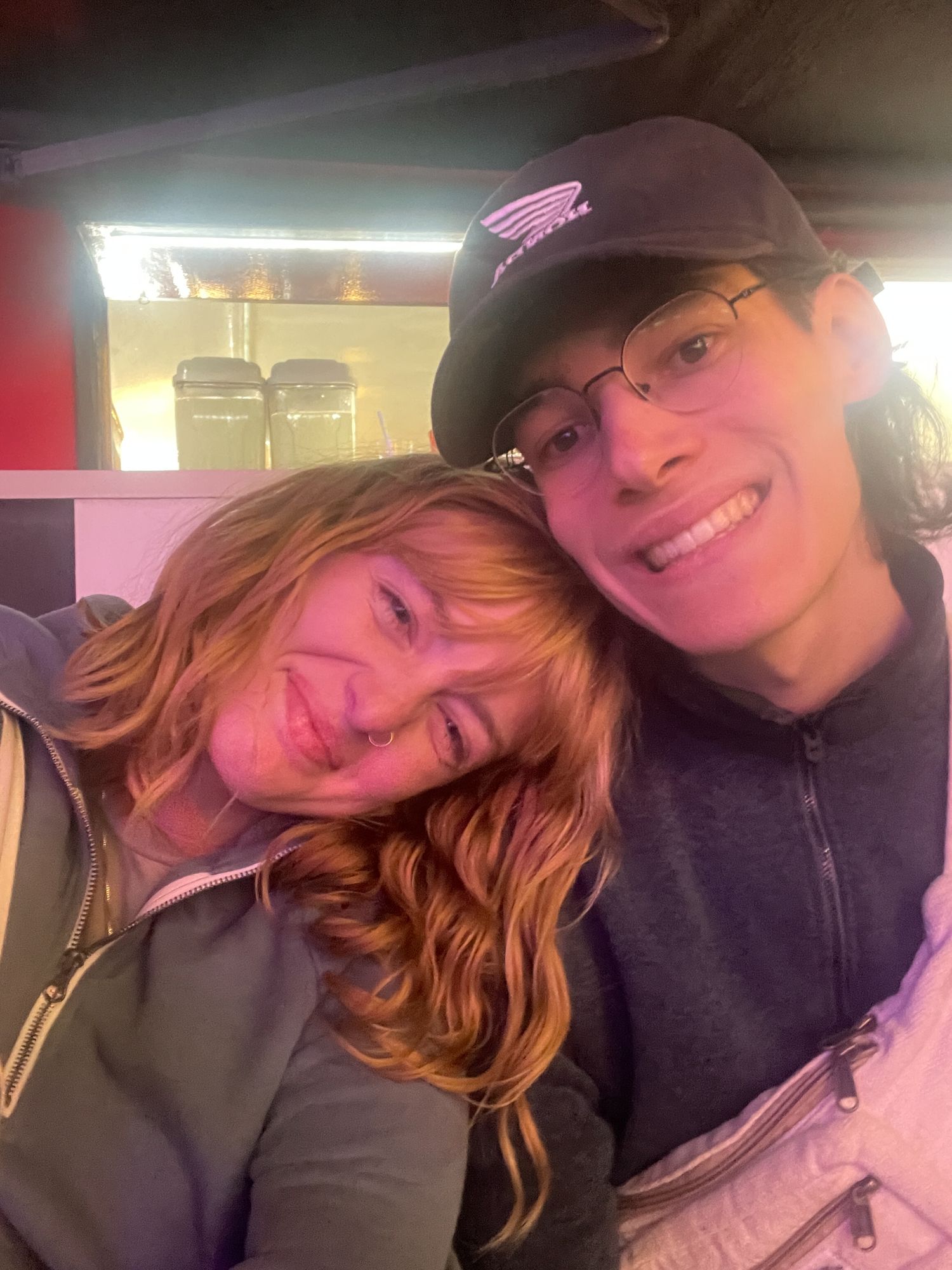 A couple takes a series of cozy selfies together while cuddling and smiling at the camera.