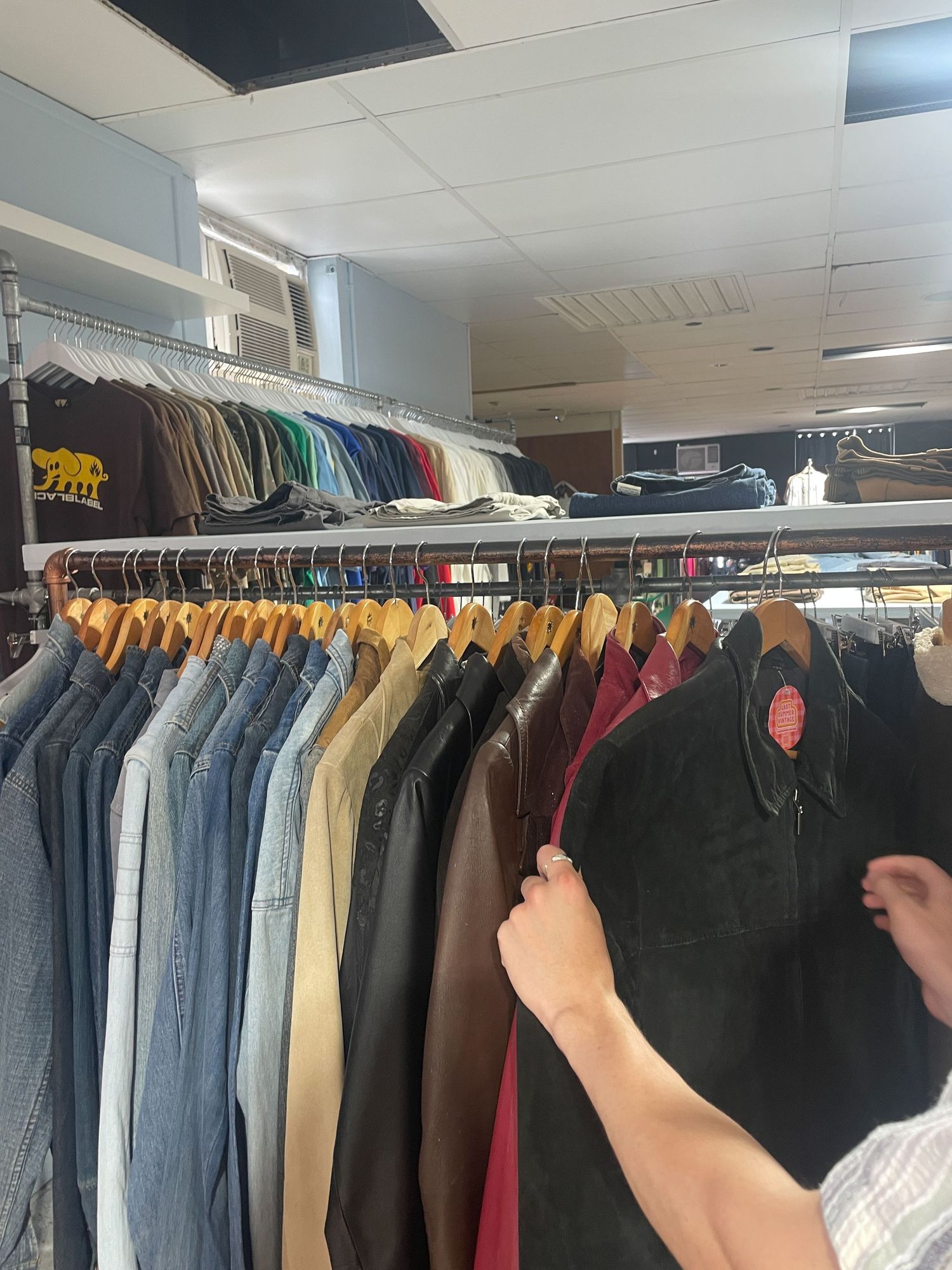 Row of coats and jackets hanging on retail clothing racks in a shop interior.