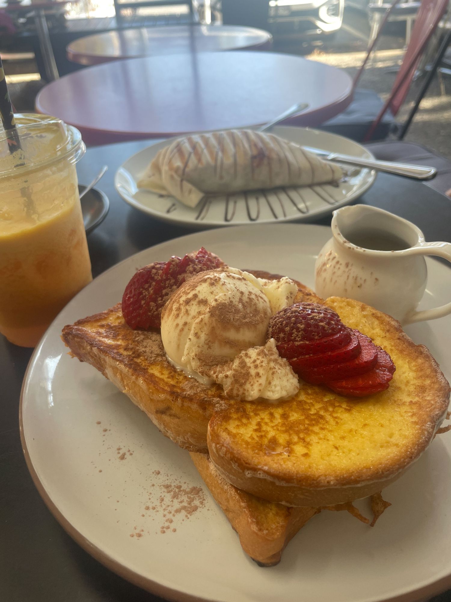 French toast topped with whipped butter, fresh strawberries and dusted with powdered sugar on a white plate.