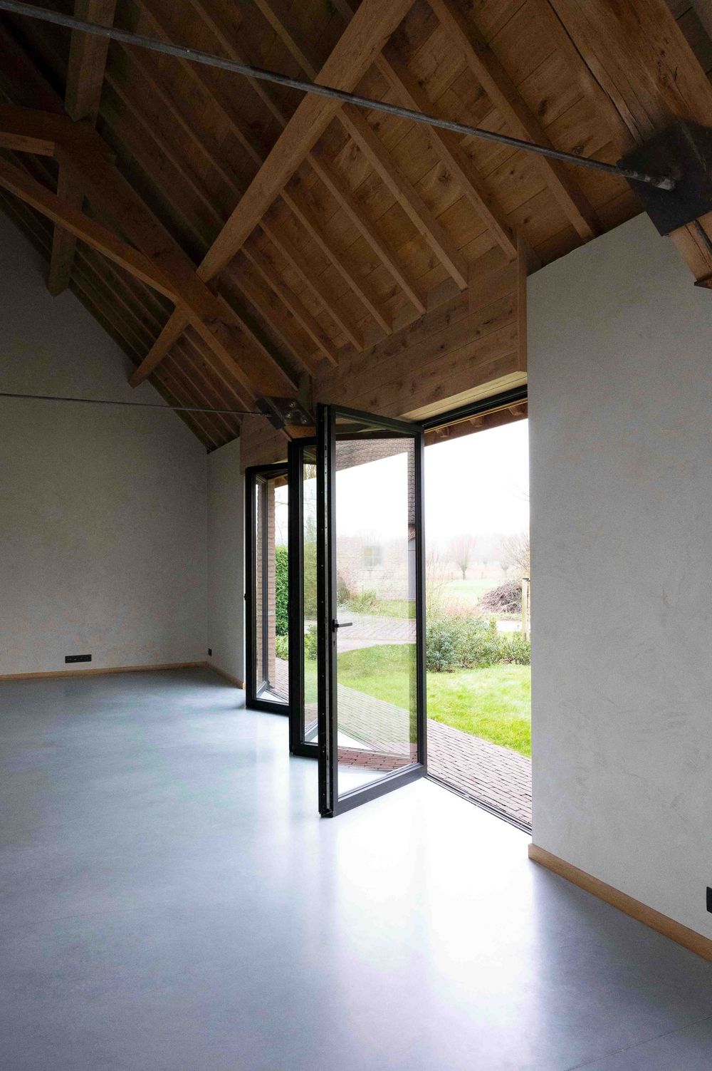 Vaulted ceiling room with exposed beams and large windows providing natural light.