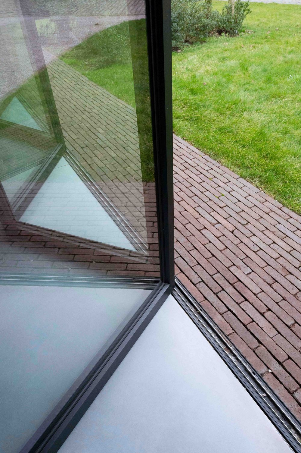 View through window showing brick paving and green lawn outside.