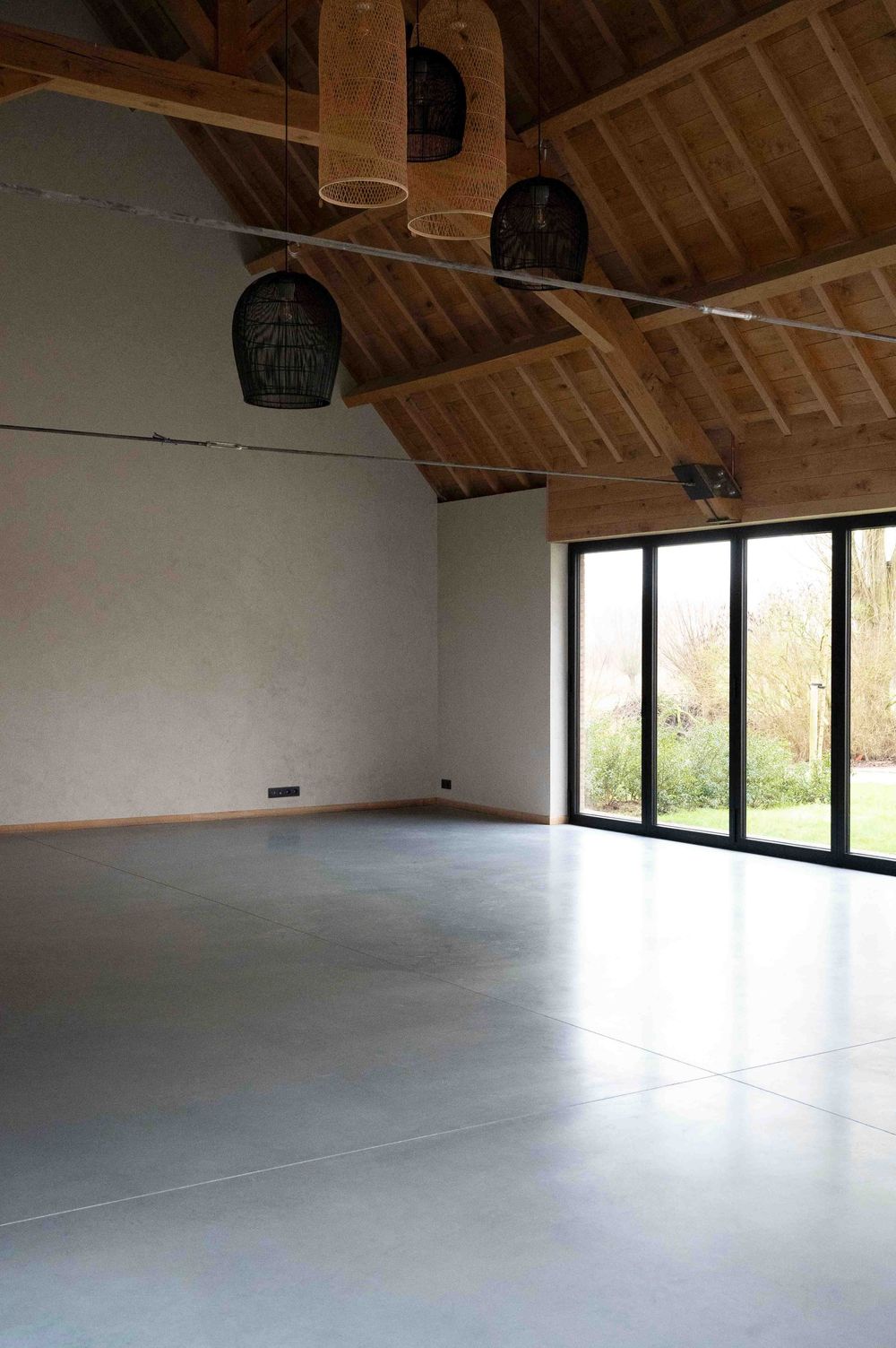 Modern open loft space with exposed wooden beams and large windows providing natural light.